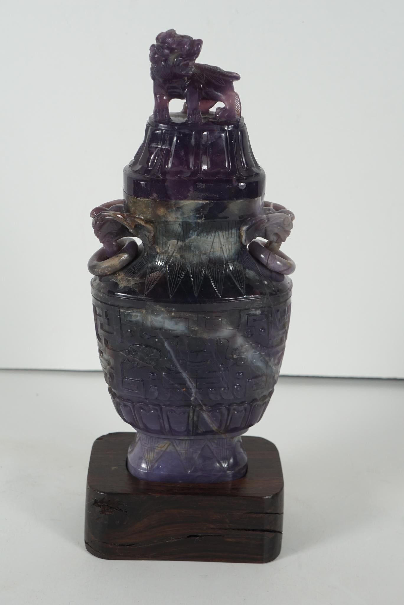 This urn, while archaistic in shape, generally is far more typical of 18th and 19th century specialty carved hardstone vases. The carving in rich veined amethyst quartz was done circa 1930-1940 and is dominated on the lid with a Kylin or mythical