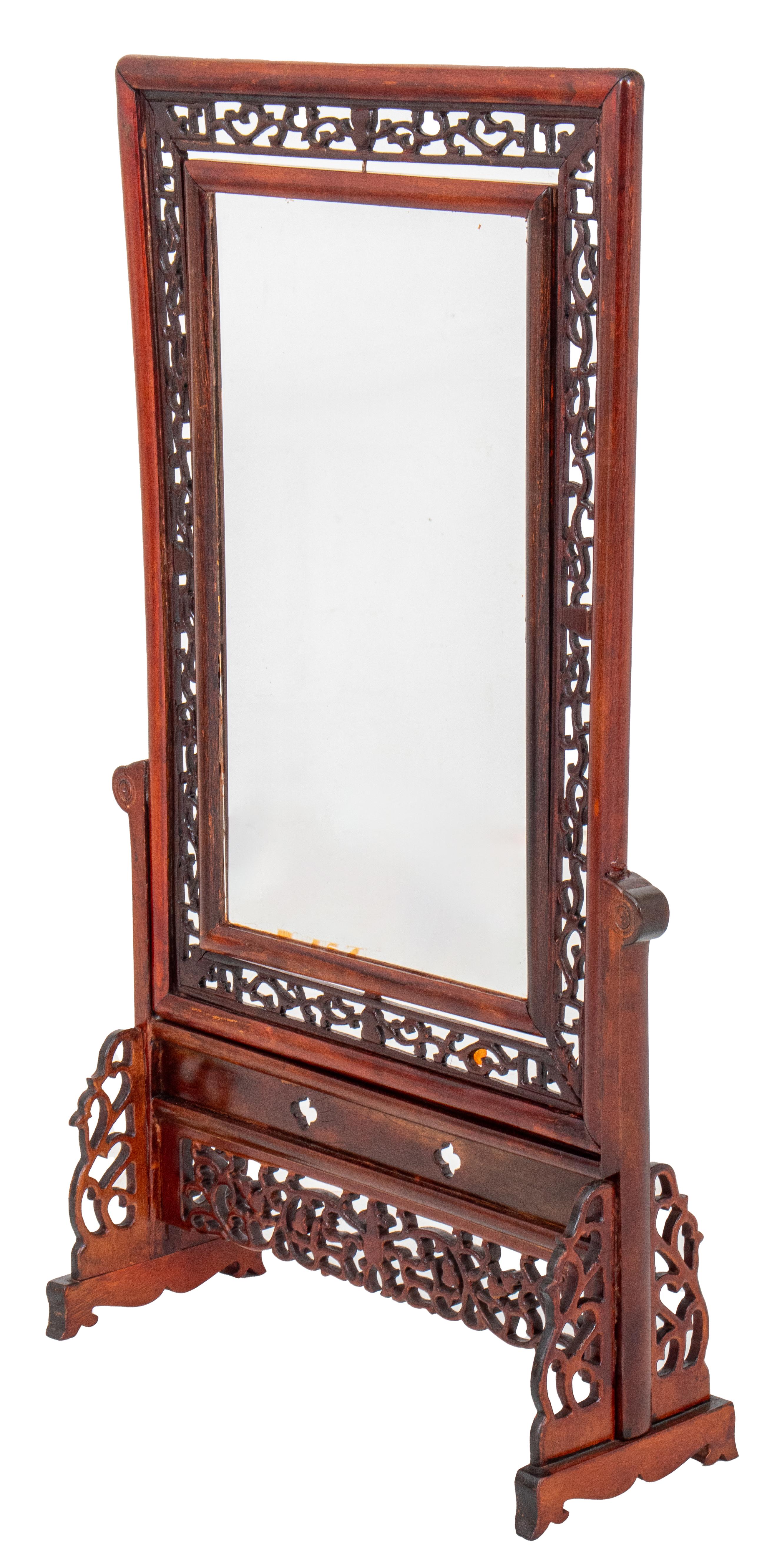 Chinese rosewood reticulated and hinged standing frame, the whole with floral decoration, the glass mounted frame fully turnable, with two volute support feet similarly carved.

Dealer: S138XX