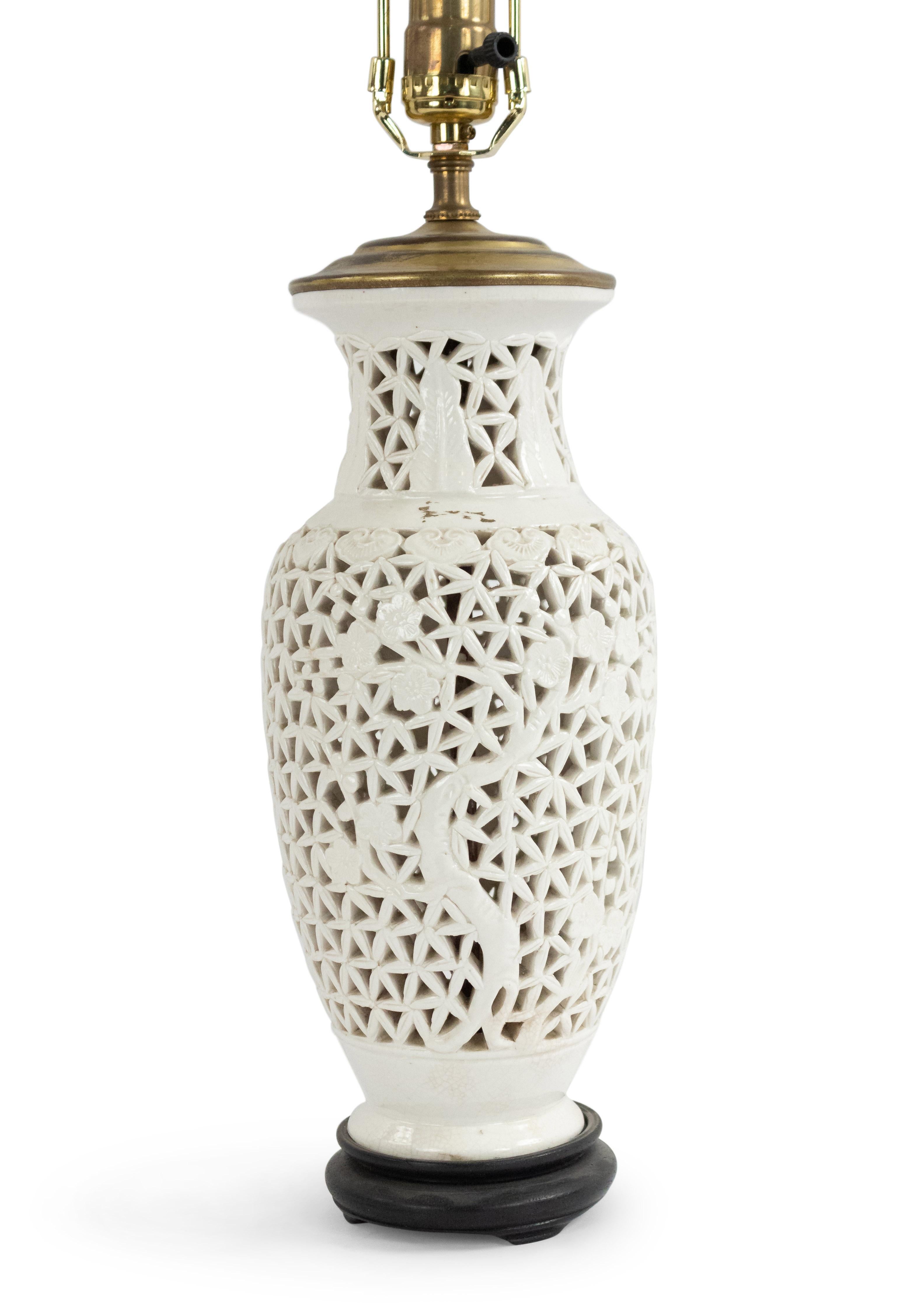 Asian Chinese-style white filigree porcelain table lamp with floral design and black round base.