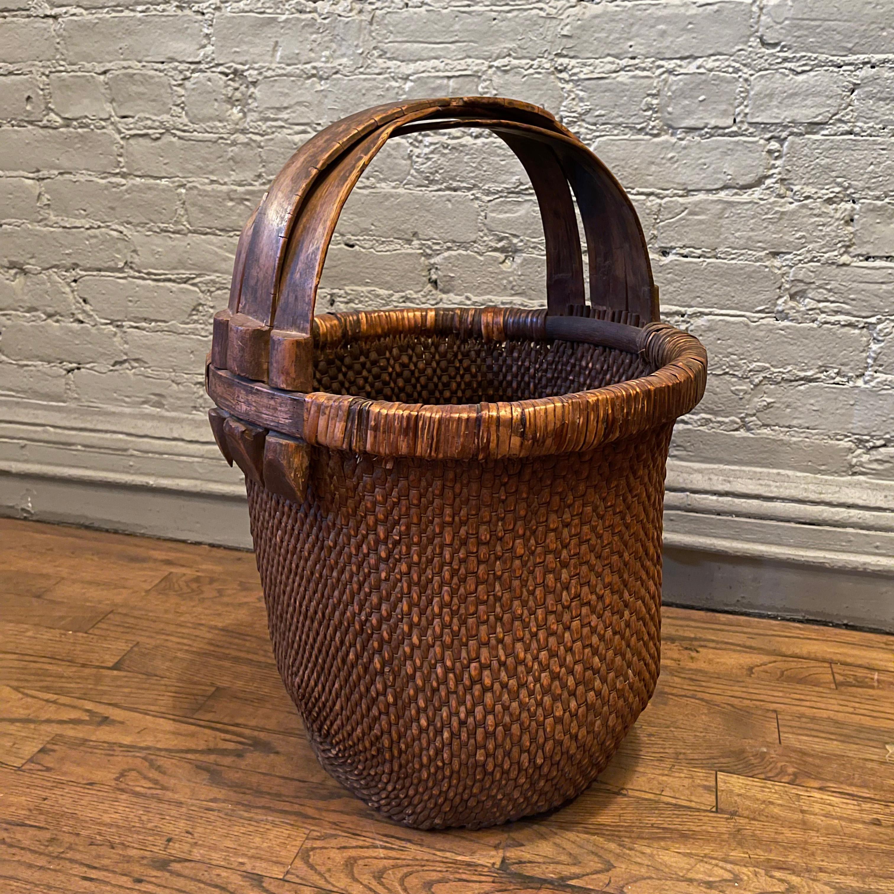 Early 20th century, rustic, Chinese rice basket is woven rush with wood frame and handle. The basket features an overall wonderful work-worn patina. Height to the top of the basket is 16 inches.