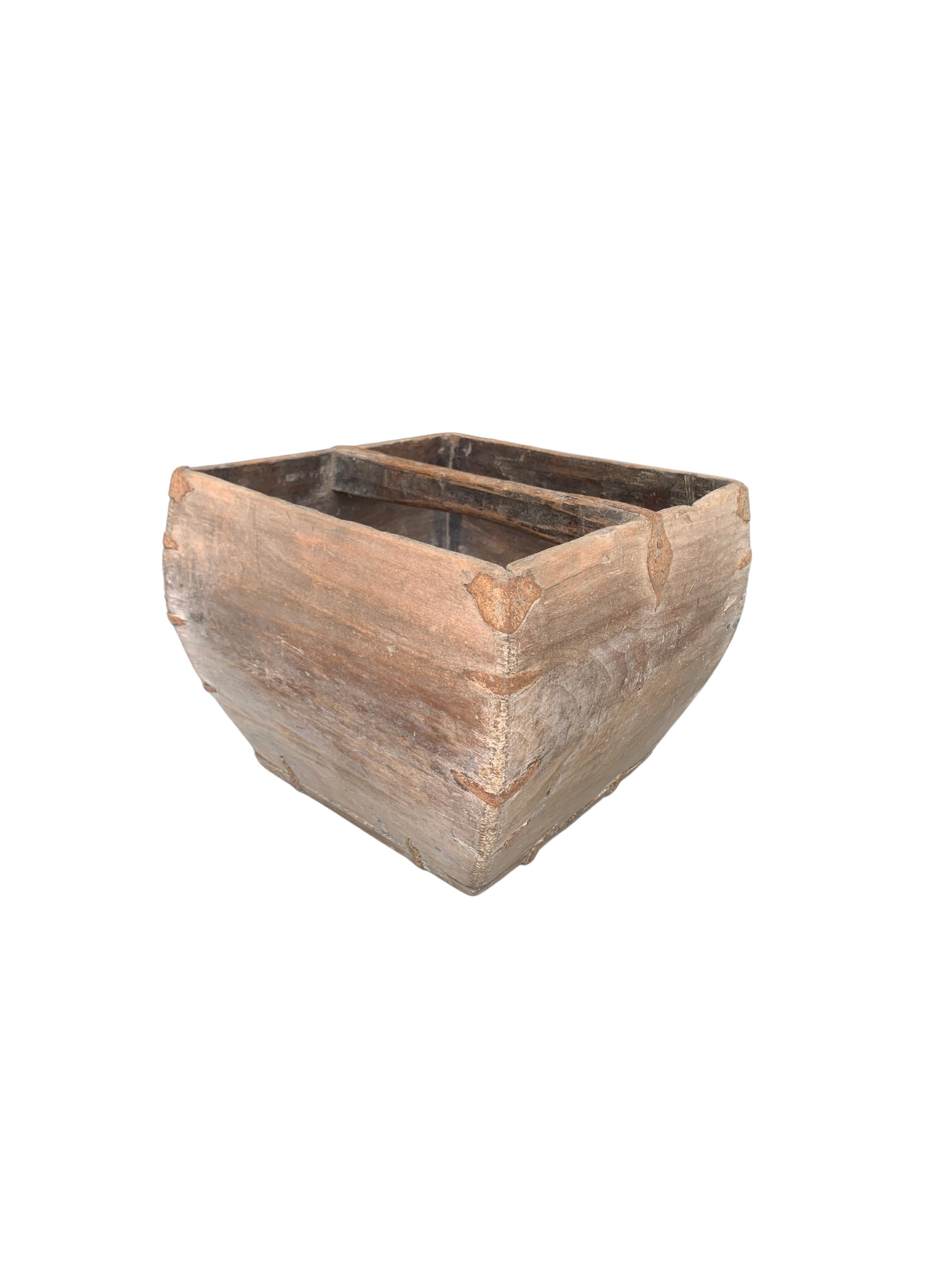 A visibly old rice measure container handcrafted more than 100 years from wood and supported by iron edges and an arched handle. There is a wonderful age related patina to the metal and wood. The container is able to hold a Dou of rice a once