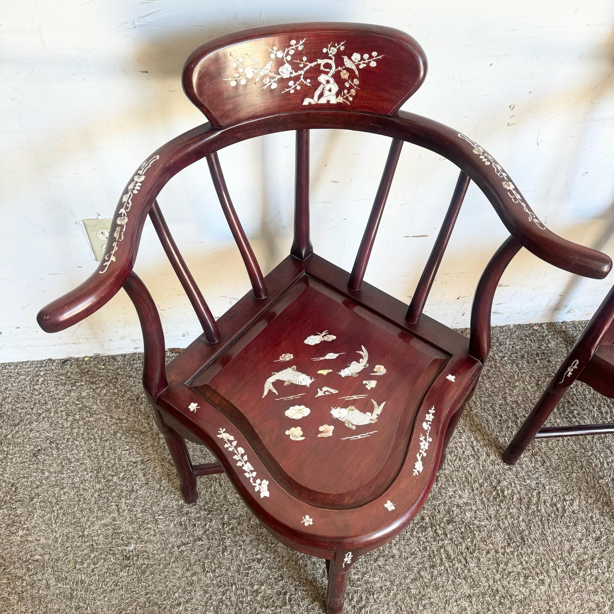 This exquisite pair of Chinese Rosewood Corner Chairs features intricate mother of pearl inlay depicting floral and bird motifs. With curved armrests and rich rosewood finish, these chairs are perfect for adding elegance and traditional artistry to