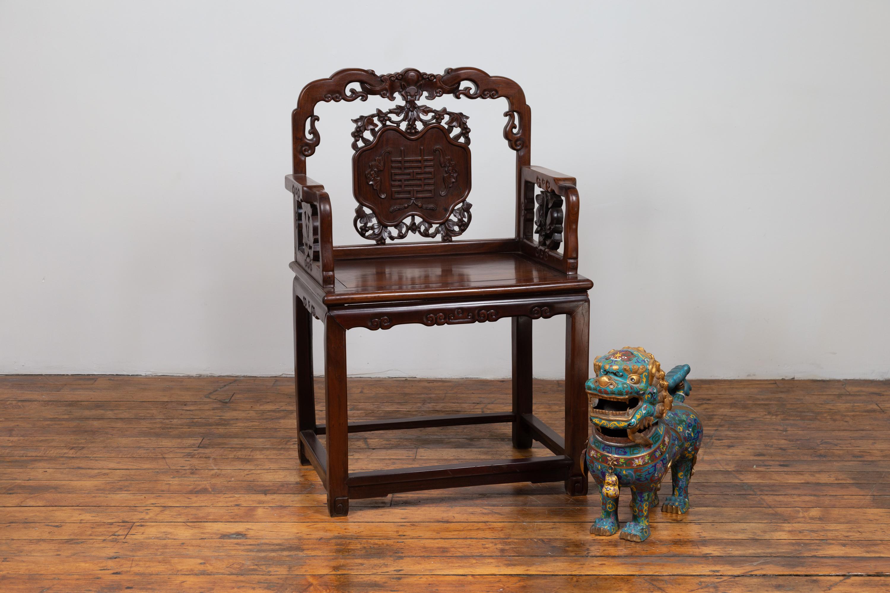 A Chinese rosewood chair from the 19th century, with hand carved splat and arms. Born in China during the 19th century, this exquisite rosewood chair grabs our attention with its stunning back, adorned with scrolling patterns and a central splat,