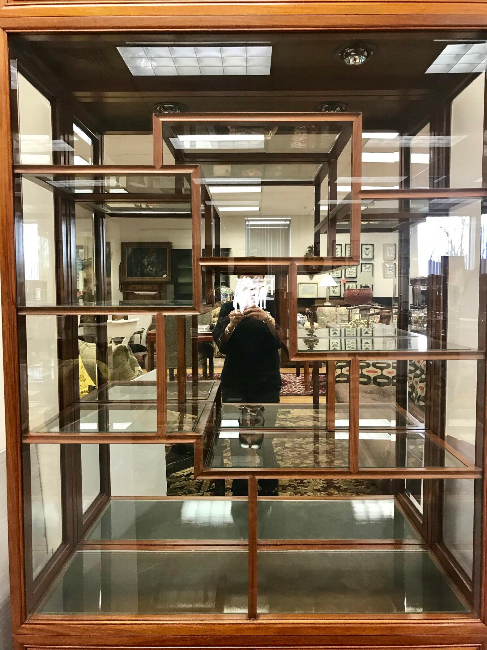 Chinese rosewood and display cabinet has glass on front, sides and a mirrored back. Interior is  accessed from side doors on either side. Lights from above illuminate your collectibles. Lower cabinet has two doors that open to more storage.