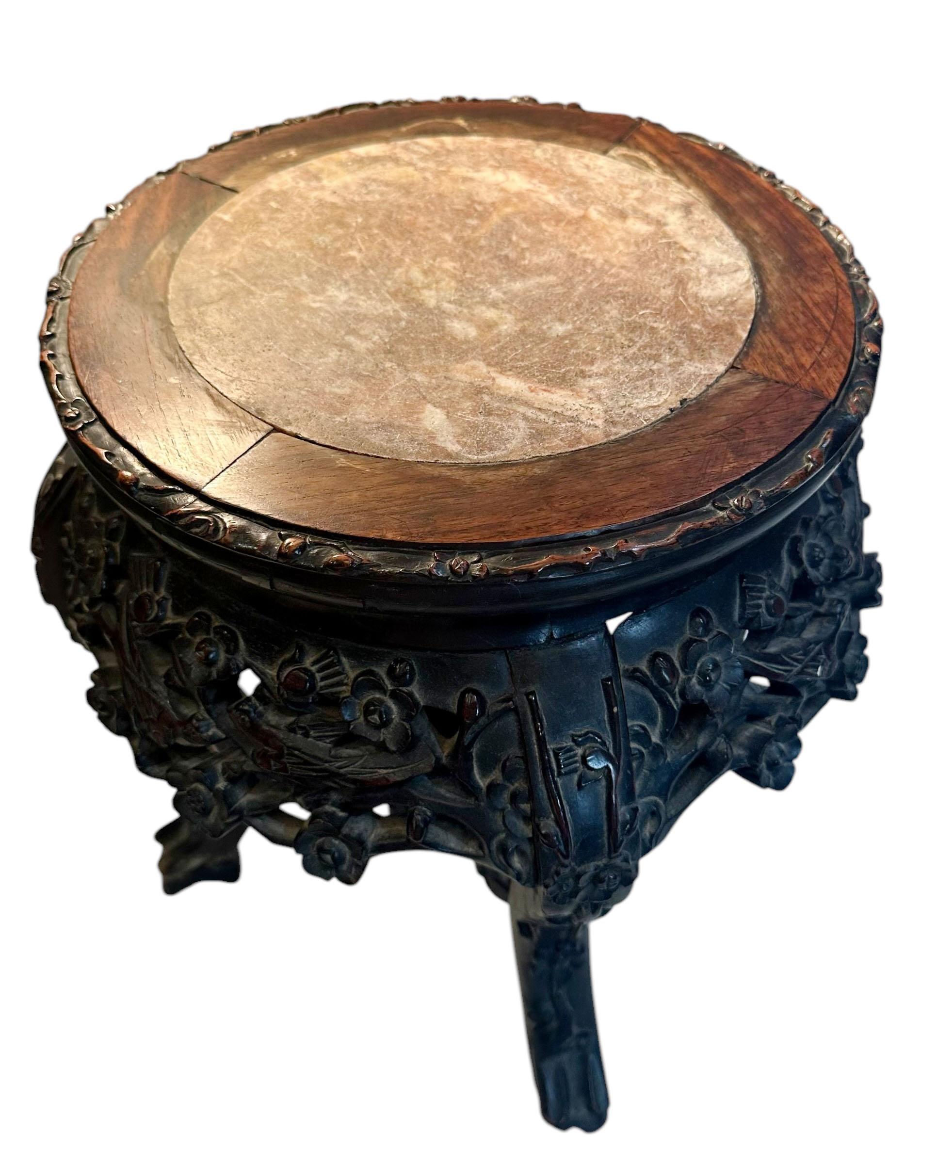 Un soporte chino de palisandro tallado con tapa de mármol, con pájaros, enredaderas y flores que parecen cerezos en flor, todos los paneles tienen pájaros. El mármol del centro mide ocho pulgadas y media y es de una especie de color topo. Alrededor