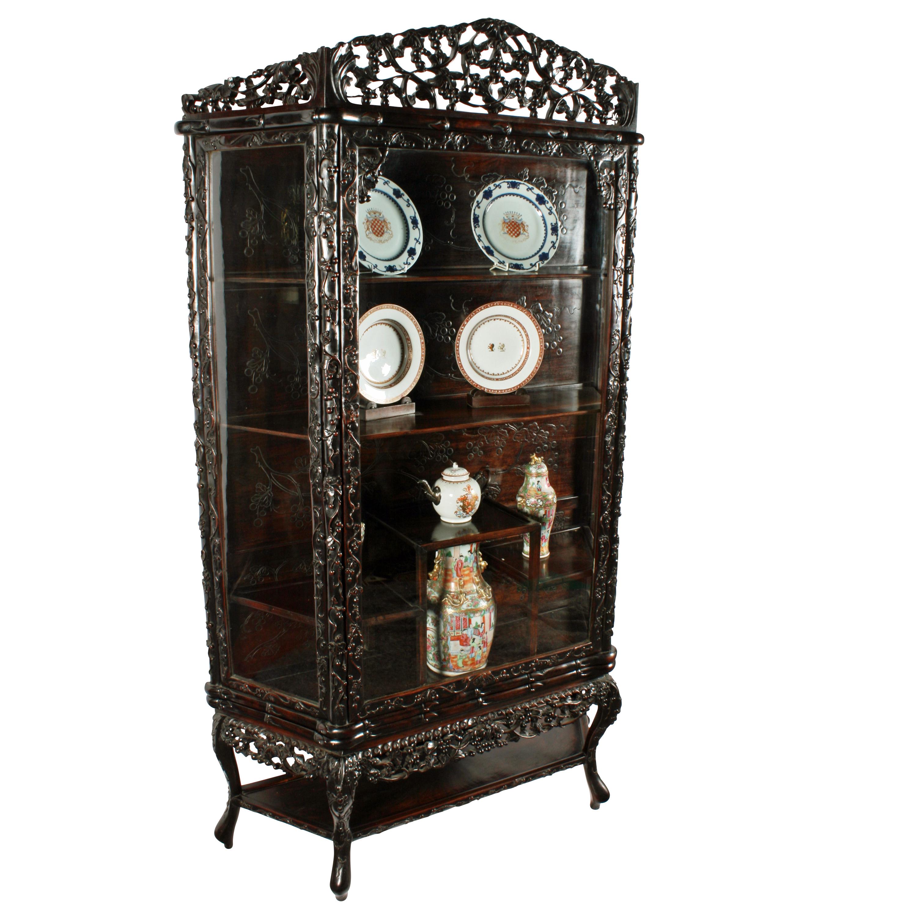 An early 20th century Chinese carved rosewood display cabinet.

The cabinet has a single glazed door and glazed panels that have frames carved with branches of flowers and fruit.

The horizontal frame above and below the door is faux bamboo