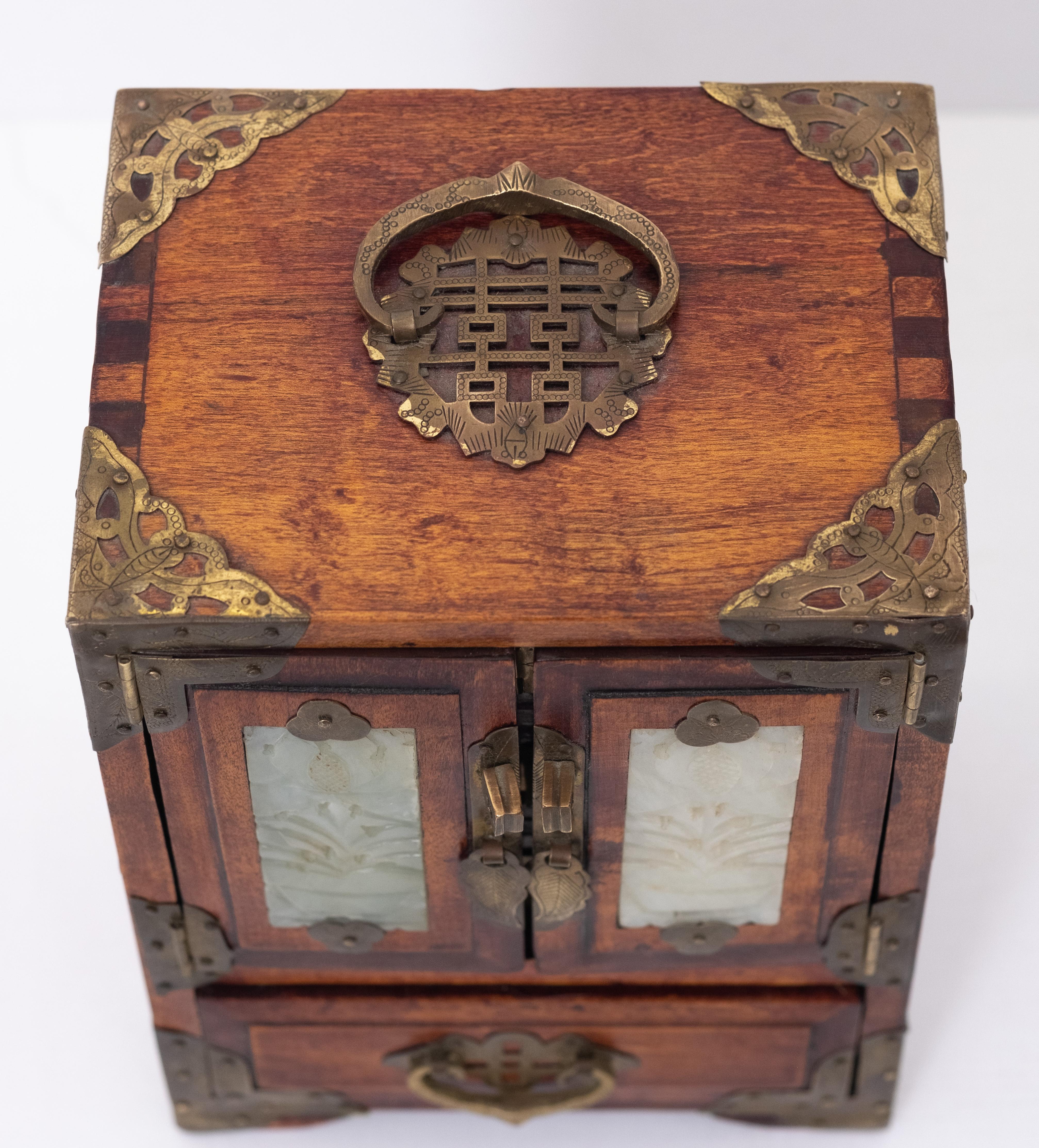 Beautiful Chinese jewelry box. Wood with brass and jade details. Original key 
inside three little drawers, with red Silk upholstery and place for your rings and bracelets. In the drawer beneath a hidden inlay tray. Lovely piece.  1960s.
 