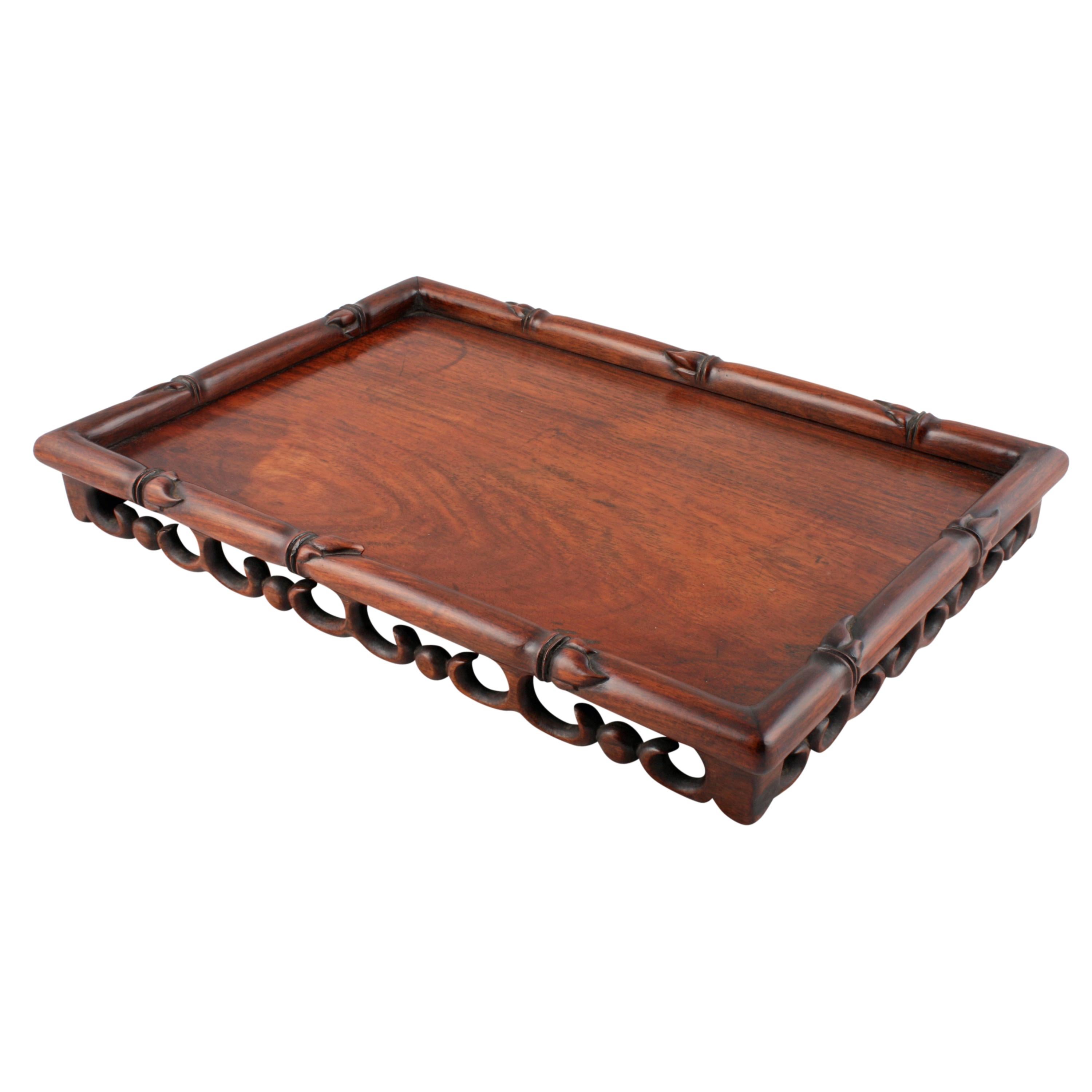 A late 19th century Chinese faux bamboo rosewood scholar's or scribe's tray.

The tray has a turned and carved faux bamboo rosewood edge and is lifted on a pierced carved scrolling gallery to all sides.

The tray is made from solid rosewood and