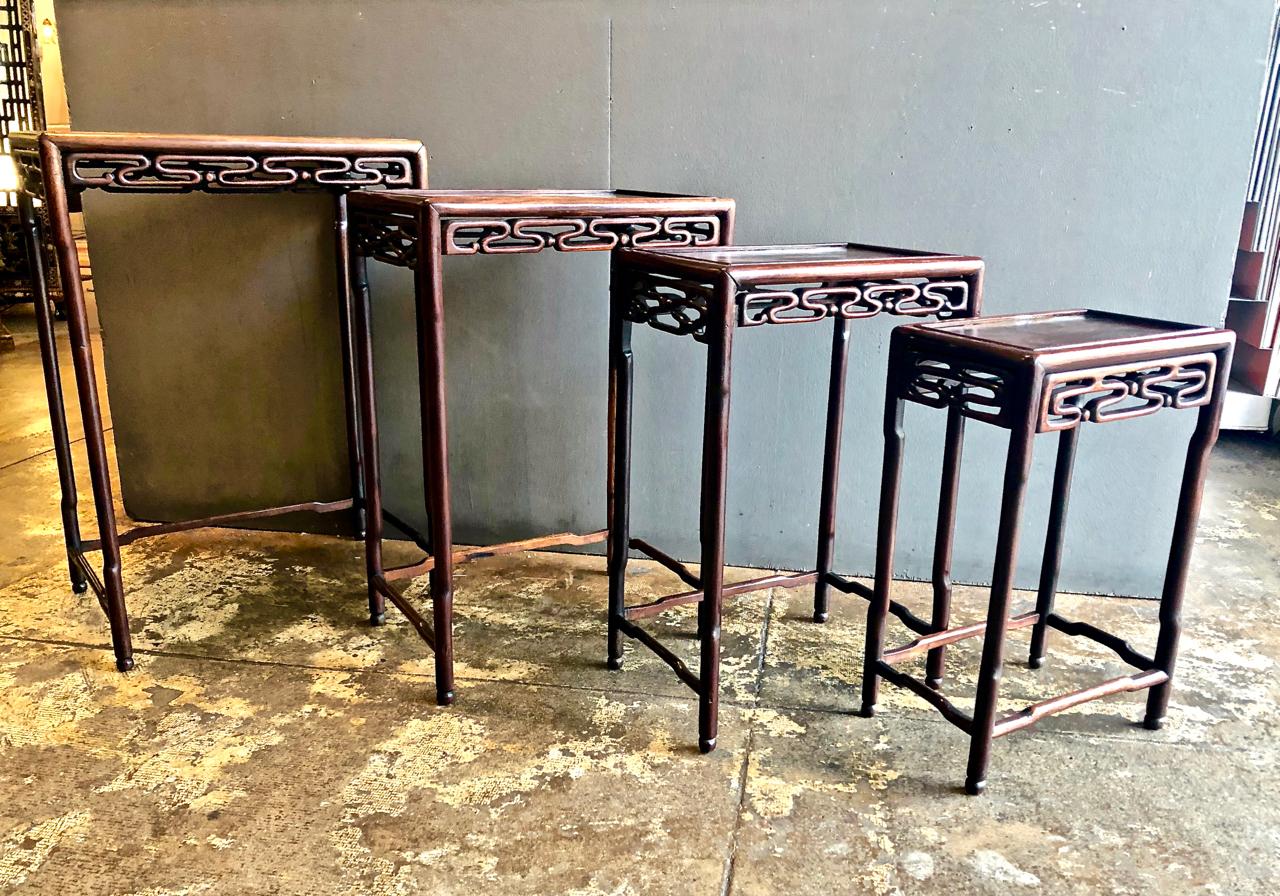 This is a good set of 4 Chinese carved rosewood nesting or quartteto tables that date to the late 19th or early 20th century. The carved wave-form skirts and shaped legs are indications of the quality level and attention to detail given by the