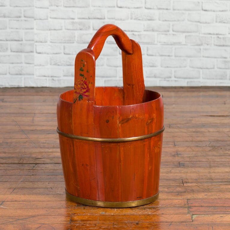 A Chinese rustic wooden bucket from the early 20th century, with large curving handle and painted flowers. Born in China during the early years of the 20th century, this wooden bucket charms our eyes with its nice proportions and warm patina.