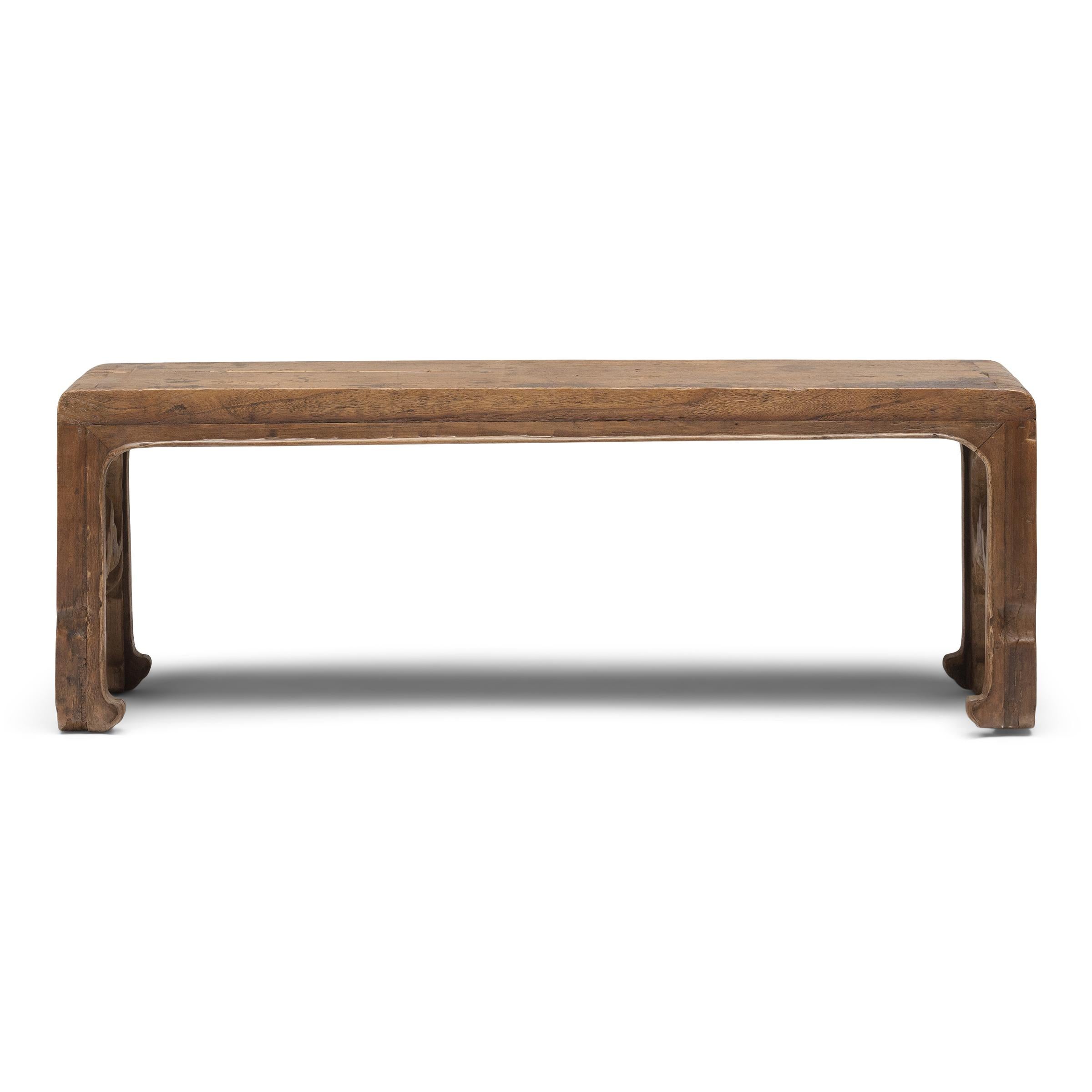 With no stretchers or spandrels, this low table flows like a ribbon, rounding the bend to form waterfall legs with openwork carvings. Known as a scroll table, this kind of low table was traditionally used for reading and writing atop a kang platform