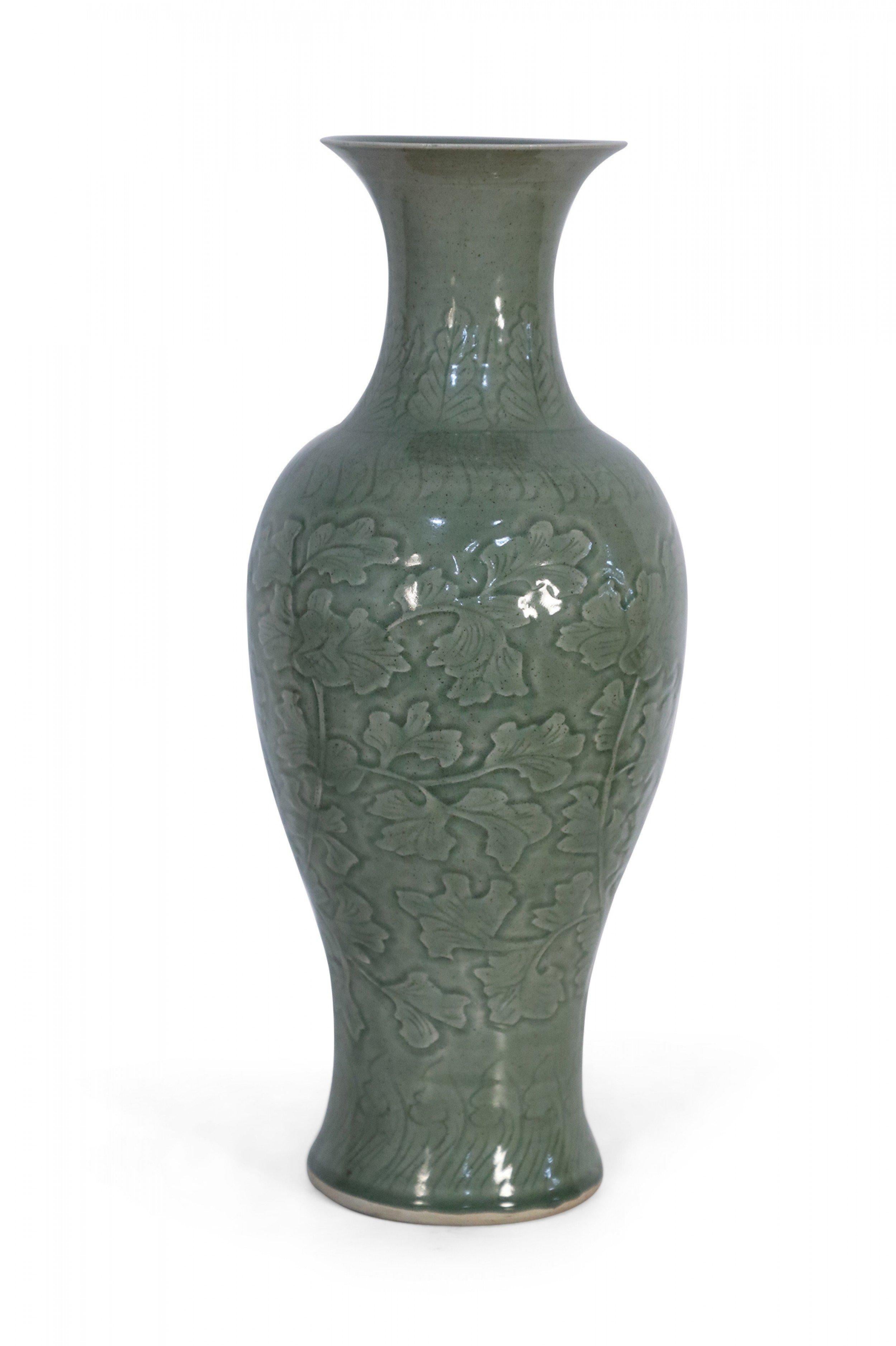 Chinese sage-colored porcelain vase decorated in an incised floral and swirling pattern that travels up the curves of the body to the concave neck, before the shape flares out once again at the trumpeted opening.
 
