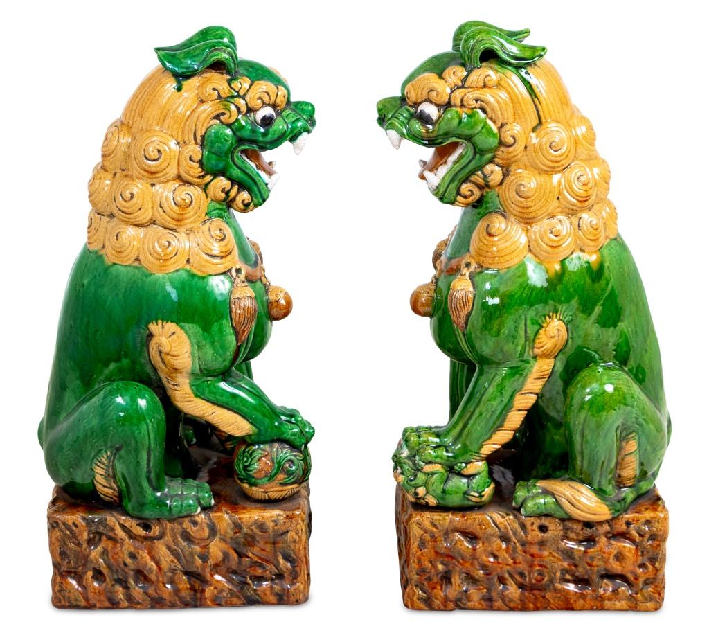 Pair of Chinese Sancai Glazed Ceramic Pho Dogs, each realistically modeled with raised paw on auspicious symbols, on a rectangular rockwork base. 23.5