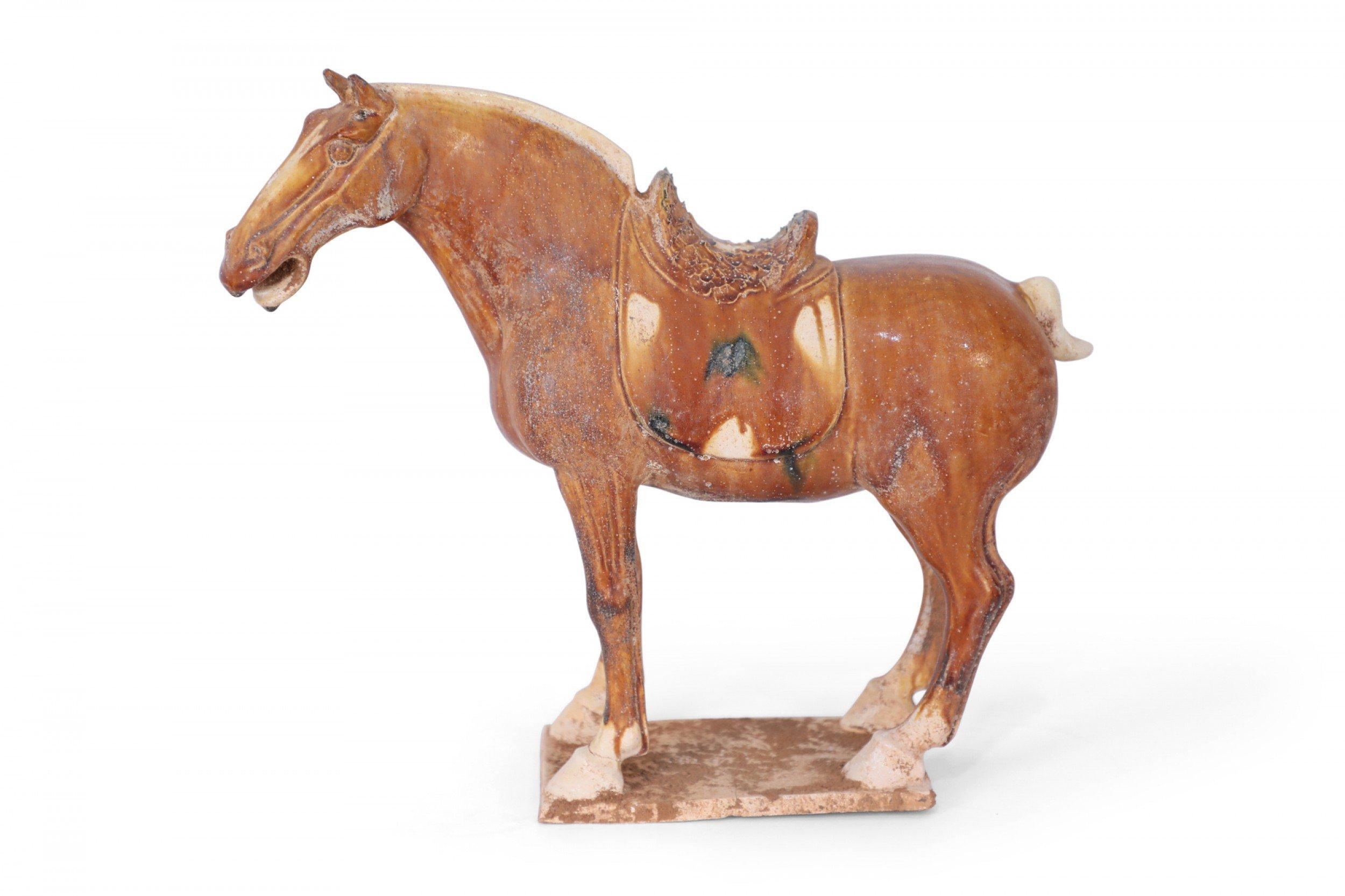 Antique Chinese Tang Dynasty-style terra cotta figure of a horse commonly used as a tomb figure for wealthy burials in the 7-8th centuries, and crafted with its traditional tri-color glaze, or Sancai, utilizing brown, green and off-white.
 