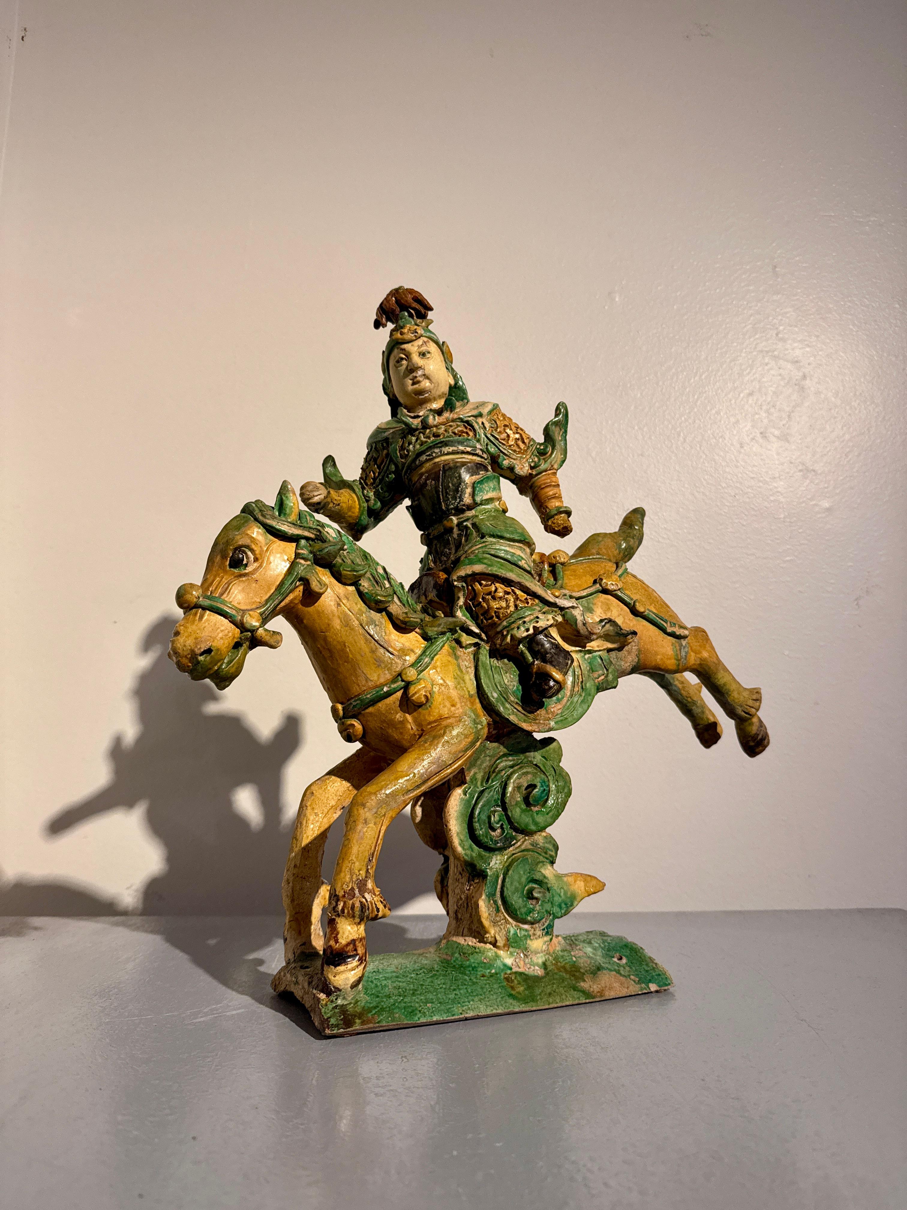 A fantastic Chinese sancai (three color) glazed pottery roof ridge tile of an armored warrior on horseback, late Ming Dynasty (1368 to 1644), circa 1600, China.

Depicting a warrior in full military regalia riding a galloping caparisoned horse and