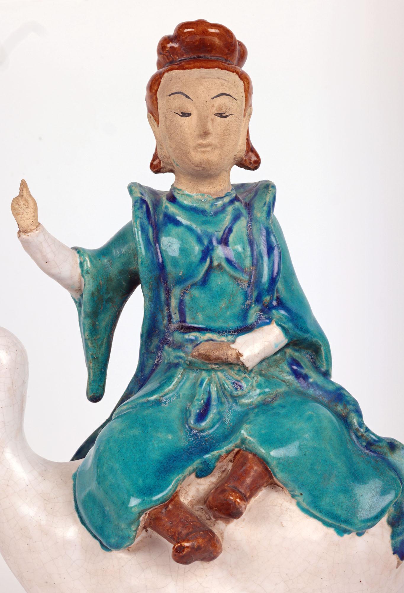 A very unusual antique Chinese pottery roof tile depicting Guanyin riding on the back of a goose and believed to date from the late Qing period. The hollow formed earthenware figure stands raised on a rounded ridge tile mounted with a lotus flower