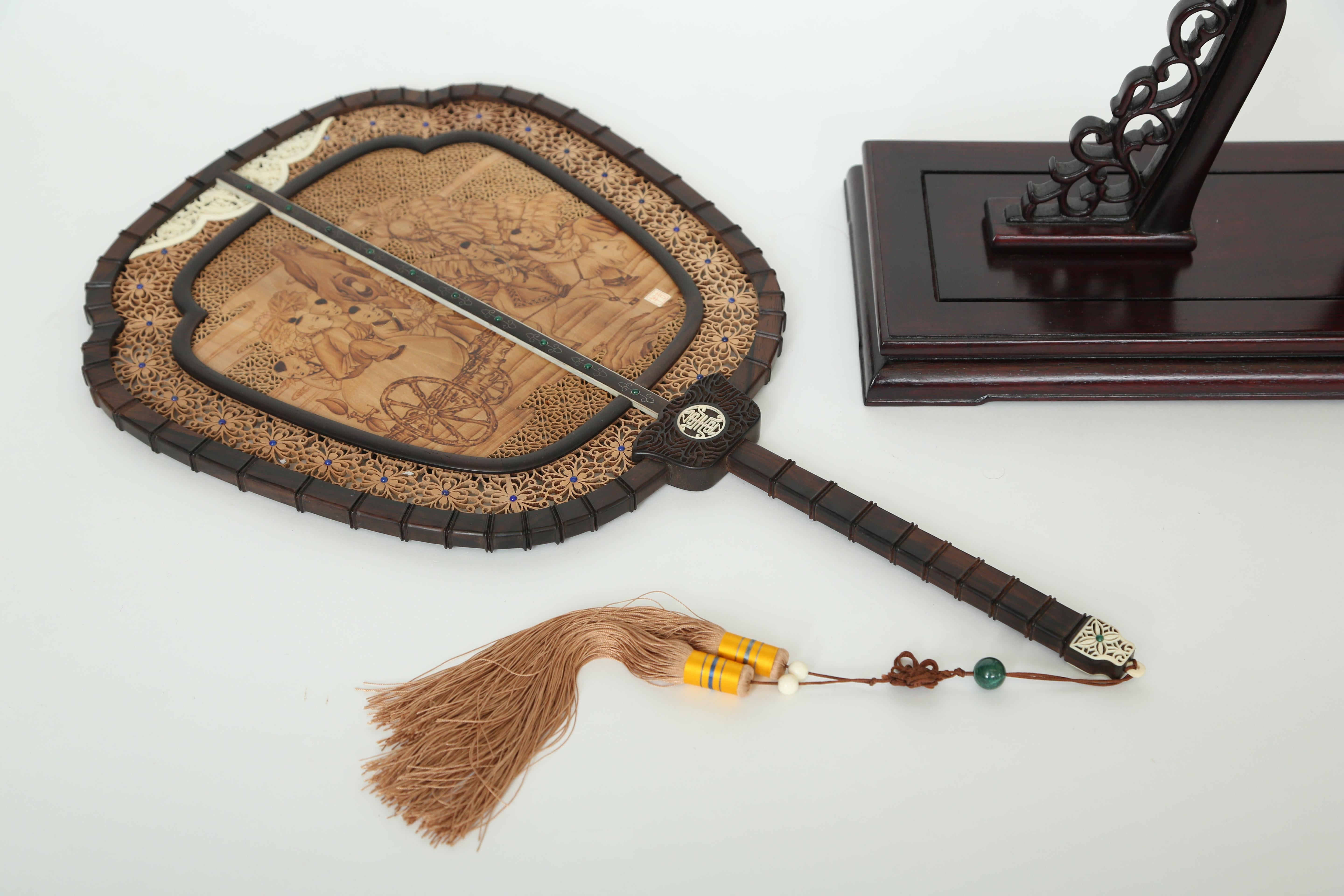 Hand held screens were to hide or protect a ladies face. This Chinese screen is made from sandalwood (which never loses its scent) in one piece scenes and cut through in pierced fretwork designs. There is a different signed scene on each side. The