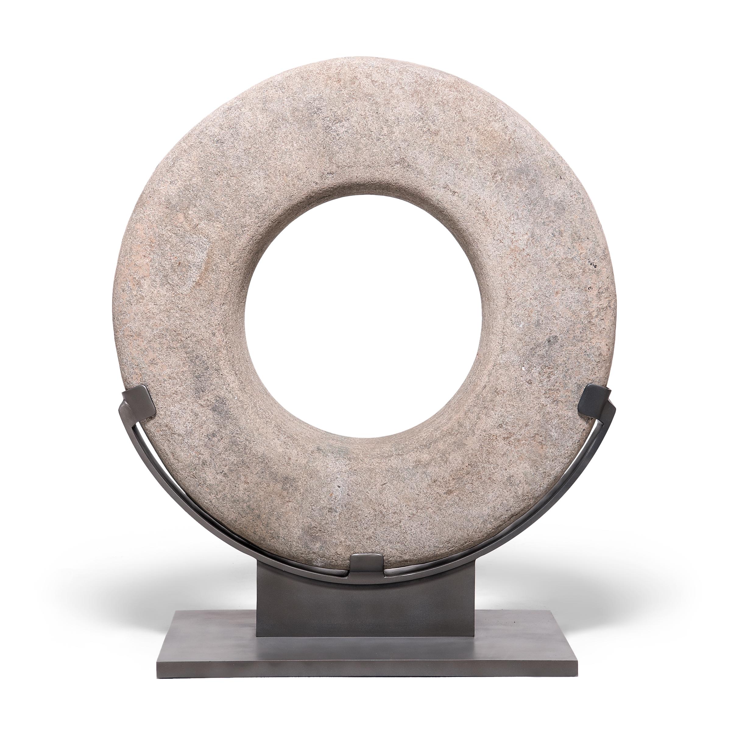 Graphic yet minimal, this elegant stone garden sculpture is actually a Qing-dynasty well head from China's Hebei province. Hand-carved from a solid block of limestone, the stone ring has a smooth surface texture and neutral, mottled coloring. One of