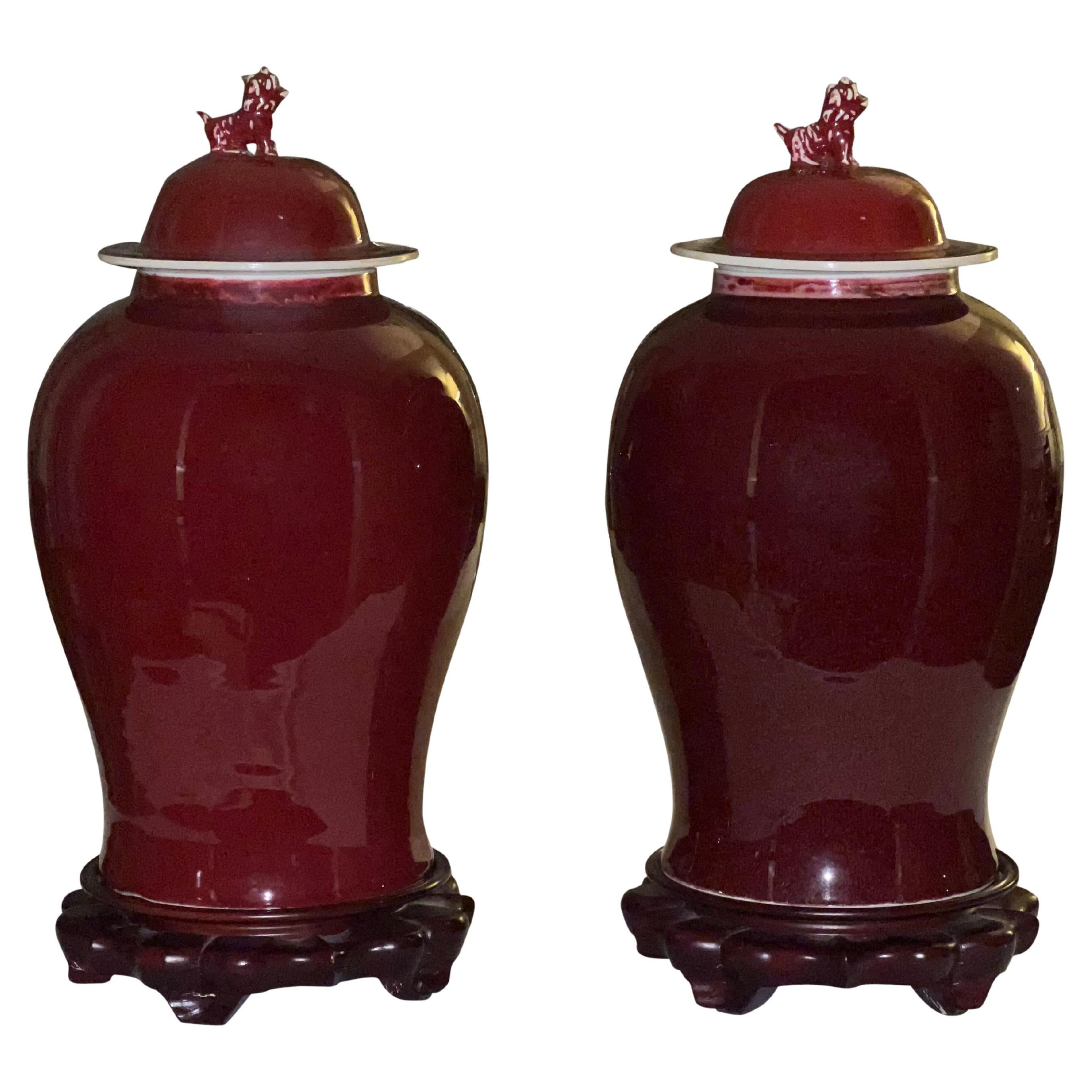 Chinese Sang De Boeuf Ginger Jars with Foo Dog Topper and Rosewood Stand, a Pair