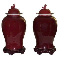 Vintage Chinese Sang De Boeuf Ginger Jars with Foo Dog Topper and Rosewood Stand, a Pair