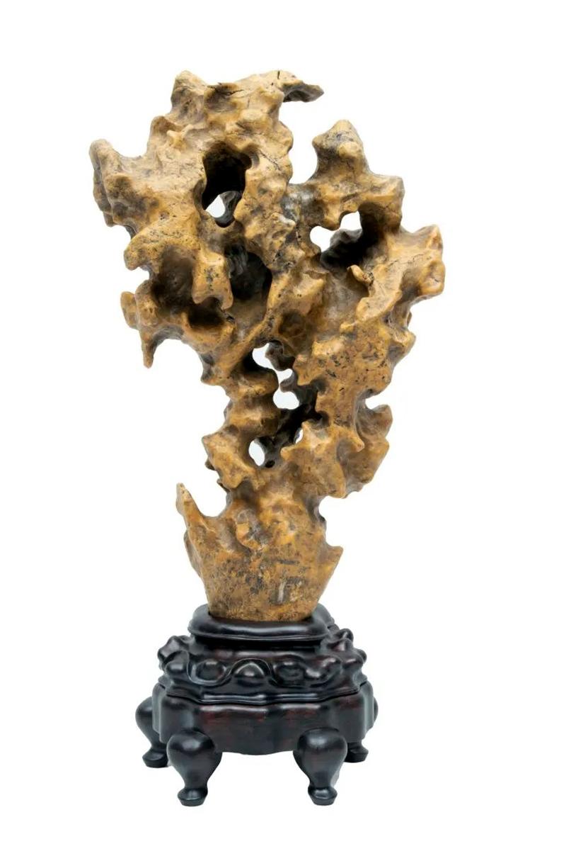 On offer is a tall Taihu scholar rock in a mushroom-cloud form displayed on a custom carved wood stand. Wonderful and well-balanced, the stone is of an uncommon waxy deep yellow color with black and white mineral deposits mixed into the texture.