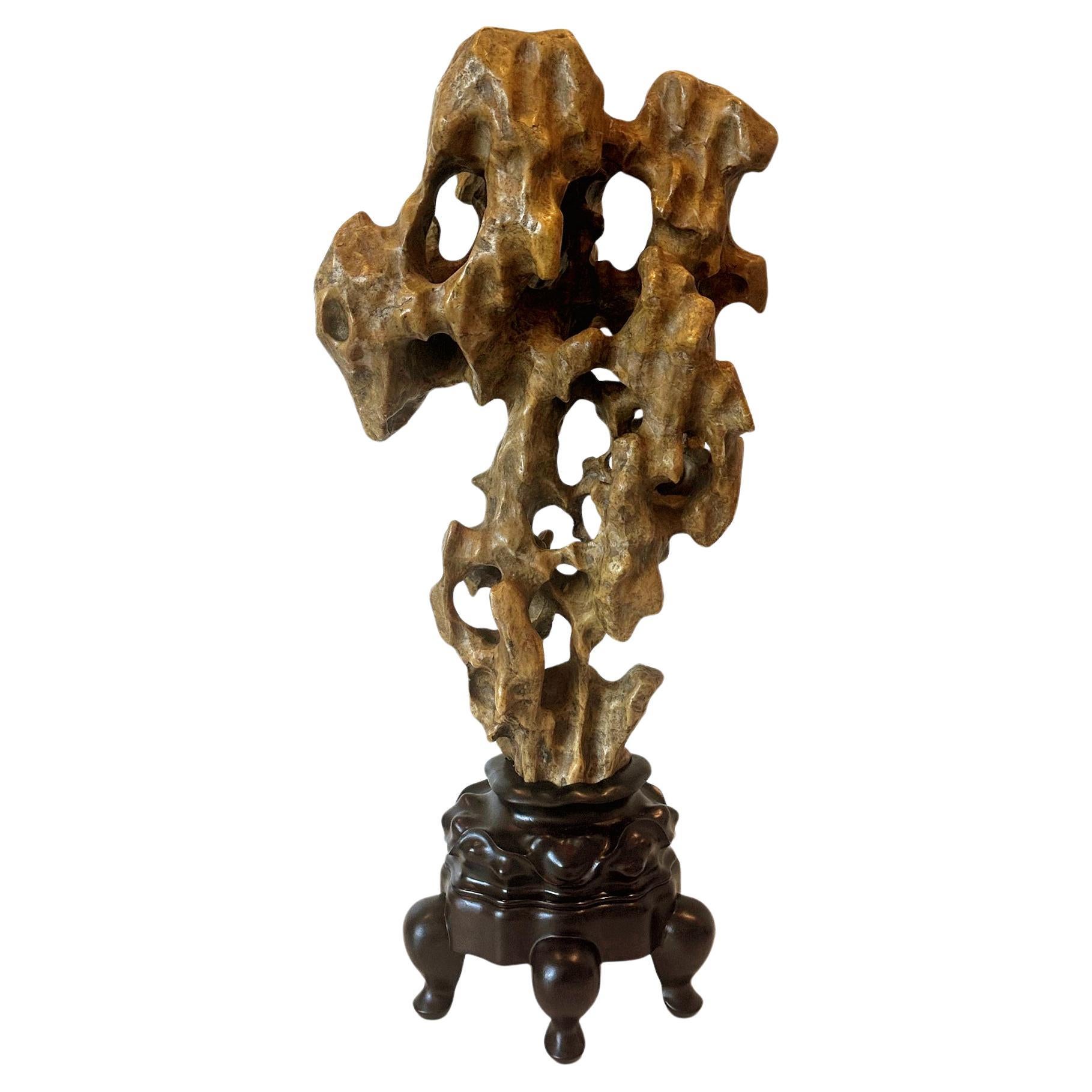 On offer is a tall Chinese Taihu scholar rock in an upright mushroom-cloud shape displayed on a custom wood stand. Well-balanced in form, the stone is of an uncommon deep yellow color with black mineral deposits nicely mixed into the waxy texture.