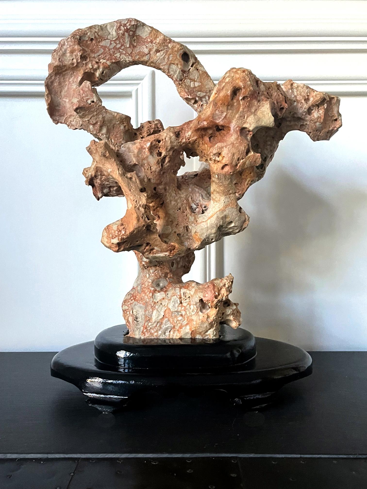 A Chinese scholar stone in an upright mushroom form displayed on a custom wood stand. Wonderful and well-balanced, the ocher and cream color stone is likely of the Taihu type. It showcases an unusual, aggregated body with highly textured surface.