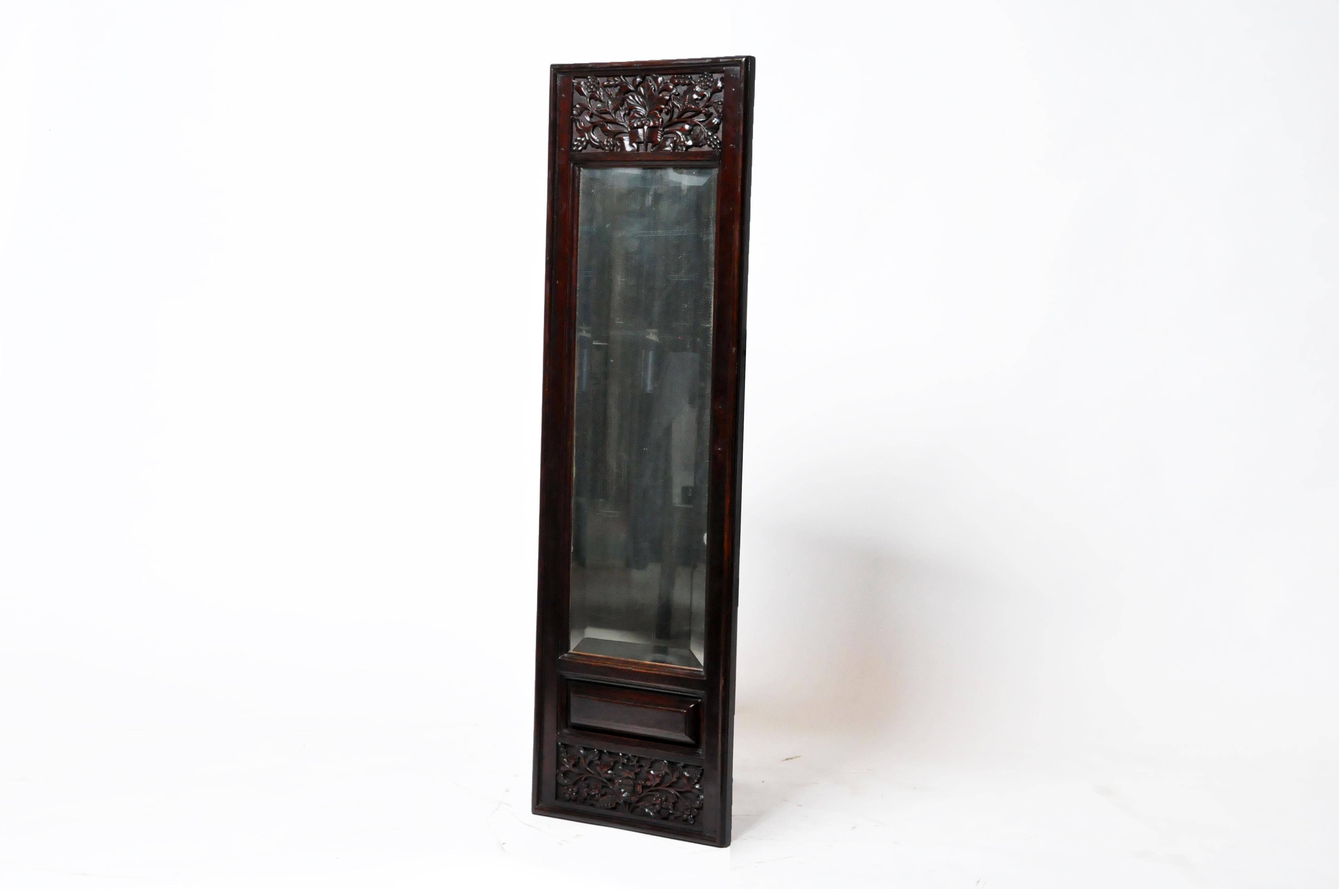 This hand-carved elm panel dates to the 19th century and once contained reverse-painted glass. It has been refitted with modern mirror glass.
 