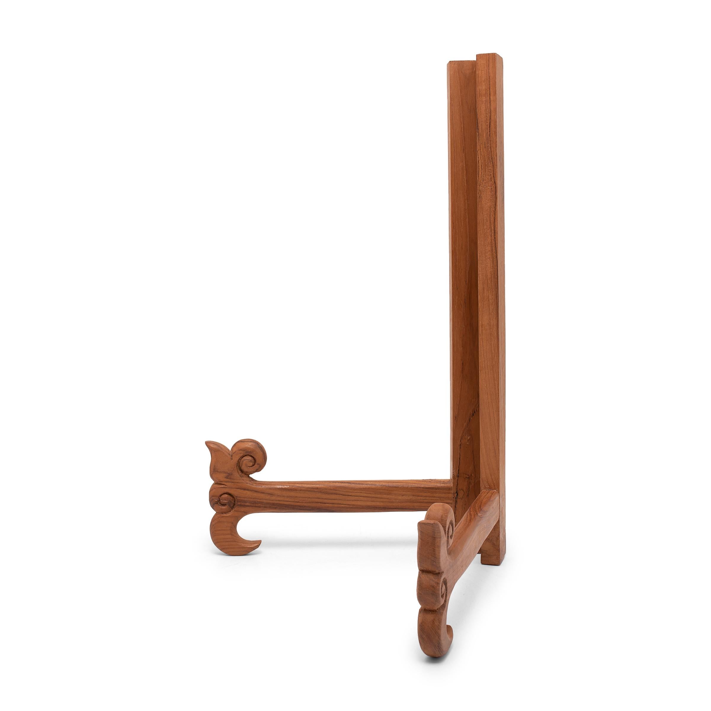 This wooden book stand is an elegant way to hold open a large book or display a work of art. The v-shaped book holder is connected by two hinges and stands on posts ending in scrollwork flourishes. Ideal for cookbooks in the kitchen or art books on