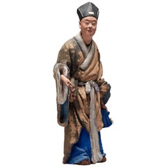 Figura china de arcilla esculpida y pintada de un hombre que sostiene una seta lingzhi