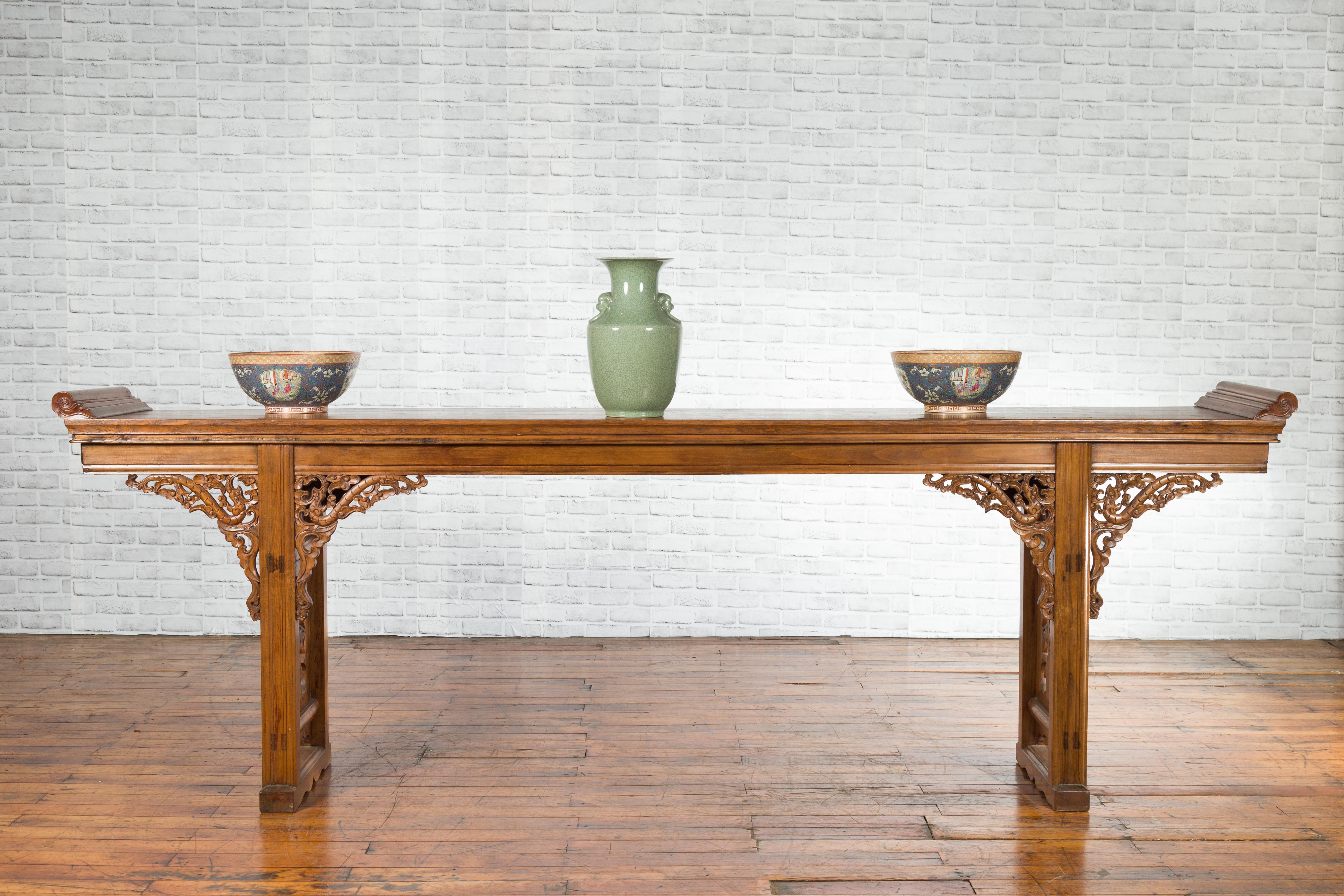 A Chinese early 20th century long elm altar console table from the Shandong province, with carved dragon motifs. Created in the Eastern province of Shandong during the early years of the 20th century, this long elm console table features a single