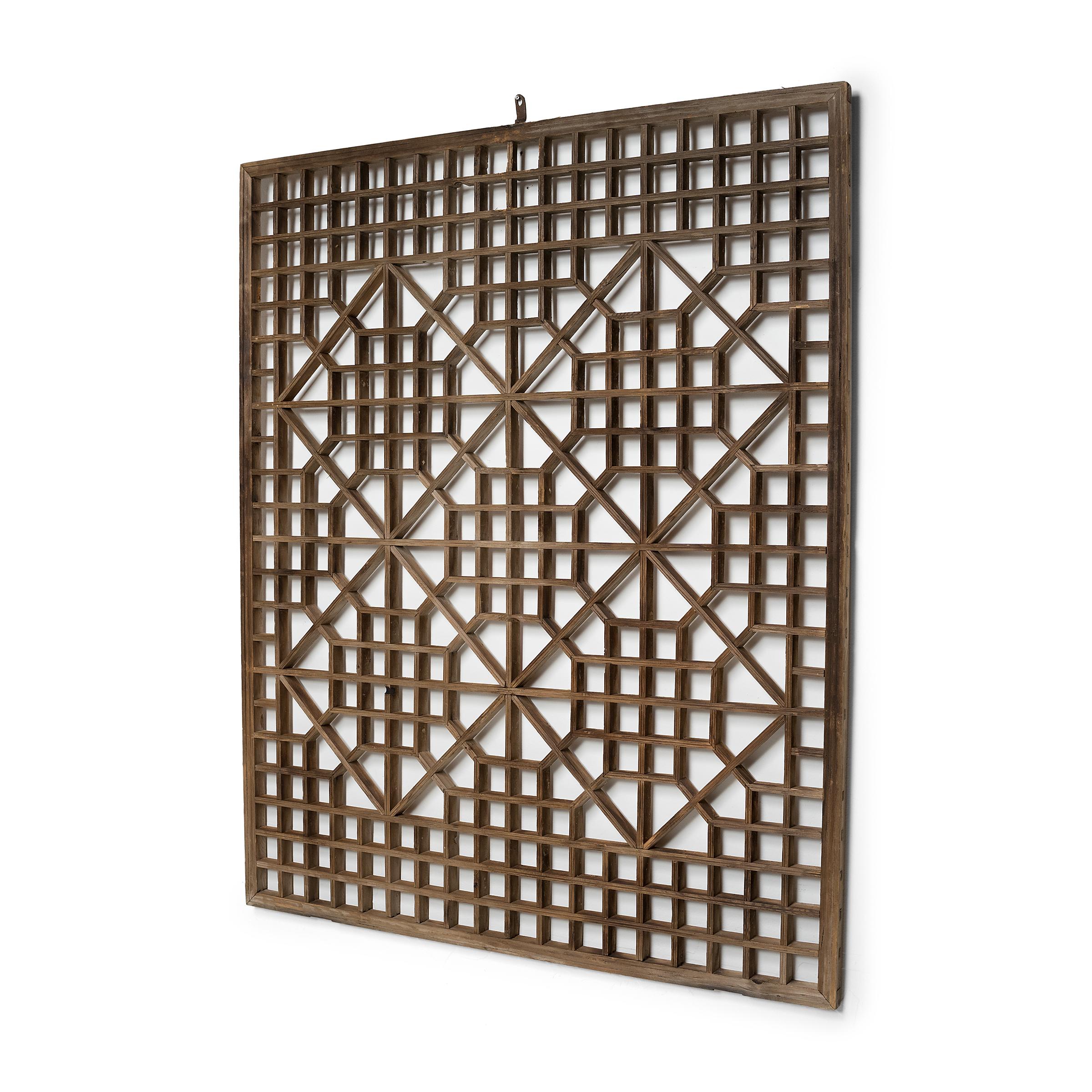 This early 20th century lattice window panel likely originated in a northern Chinese home with neutral and balanced interiors. The geometric lattice pattern is linear and open, and was designed to allow light and air into a room while maintaining