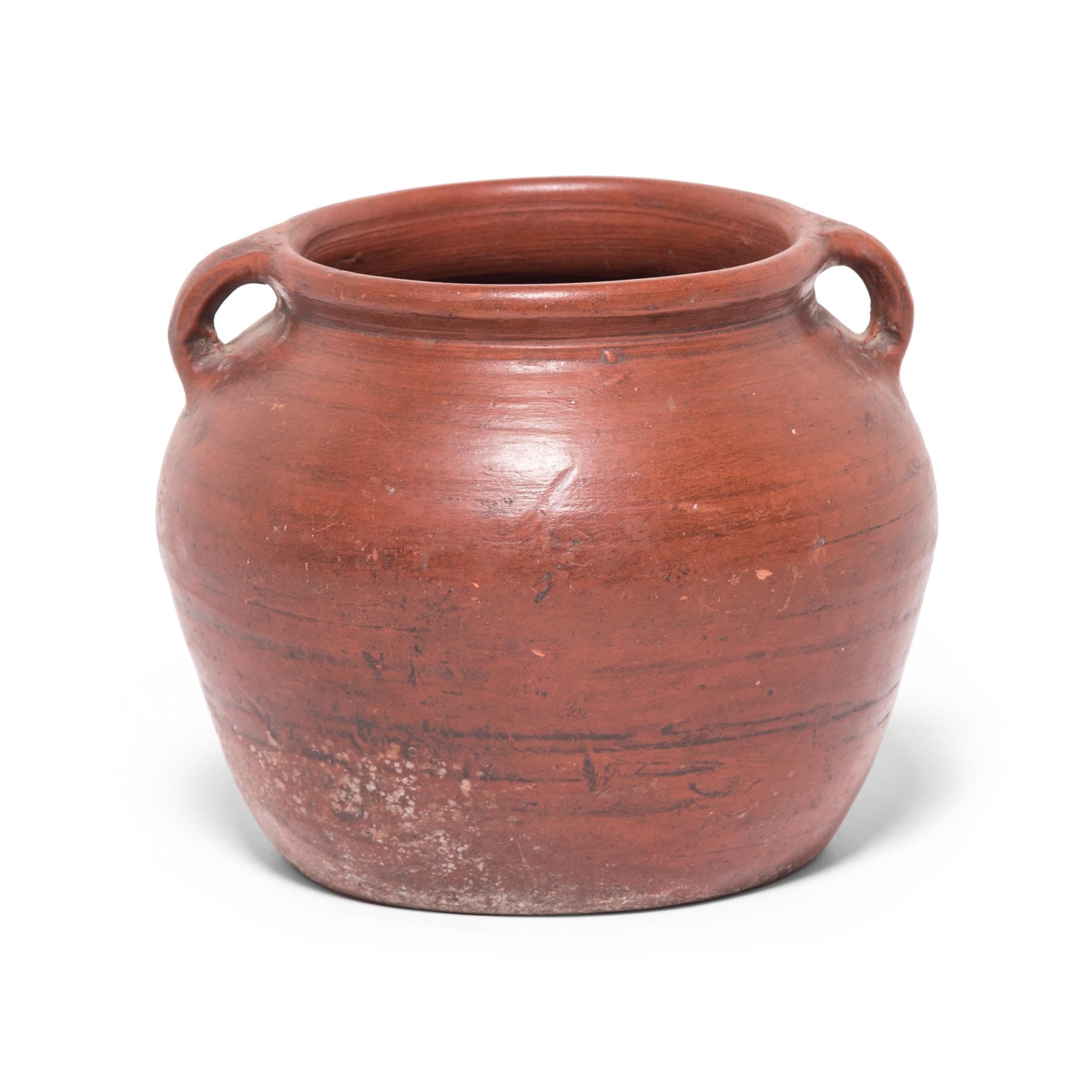 Based on vessels fired in ancient Chinese kilns, this jar's perfect proportions haven't changed much since the Bronze Age. Keeping in the tradition of its predecessors, this early 20th-century ceramic vessel is glazed with a slip of red clay,