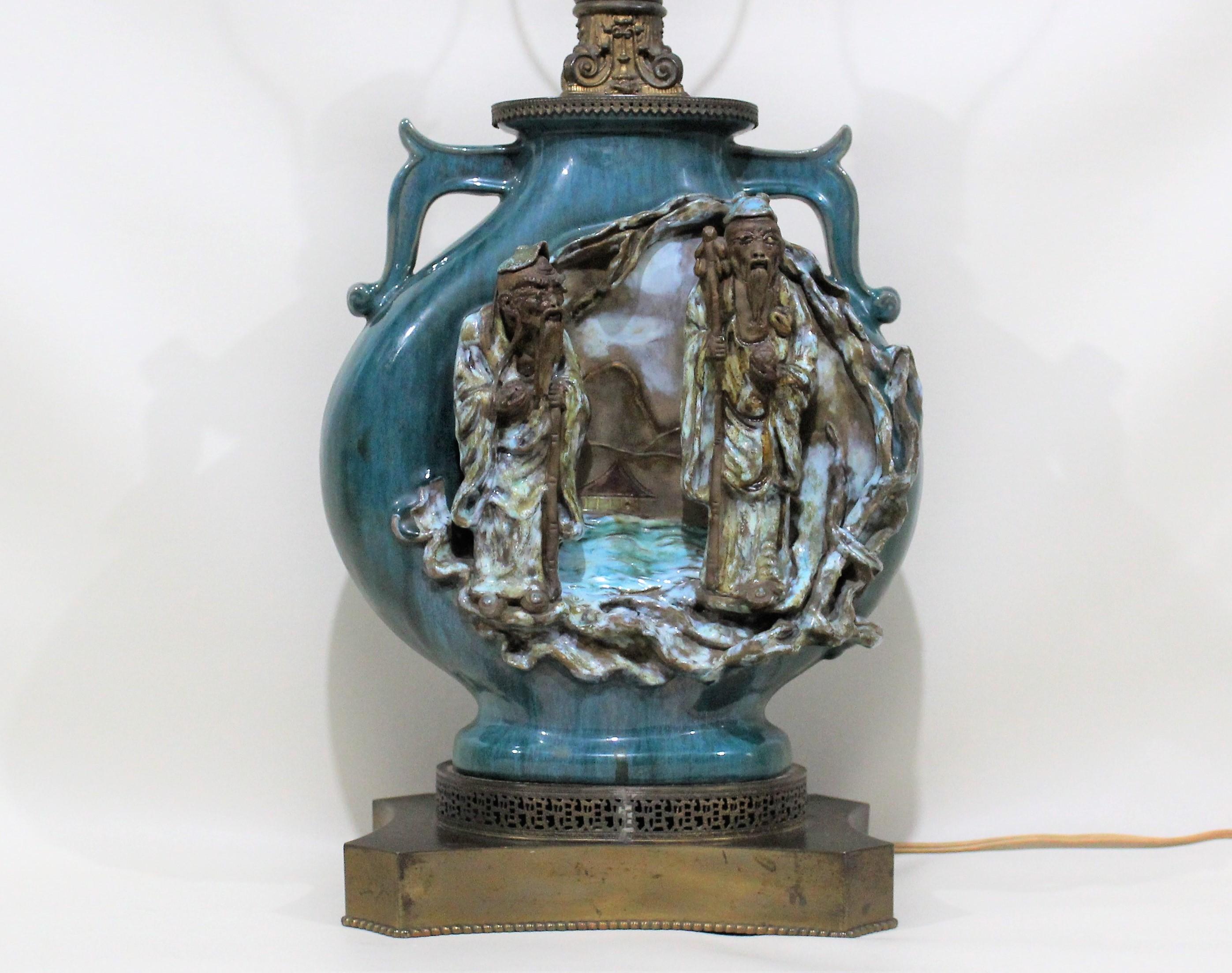 This hand sculptured, circa 1900 Chinese Shiwan pottery lamp depicts two Chinese scholars within a country landscape. Sometime in the mid-20th century the previous owner properly converted this large Shiwan pottery vase into a lamp. On the back are