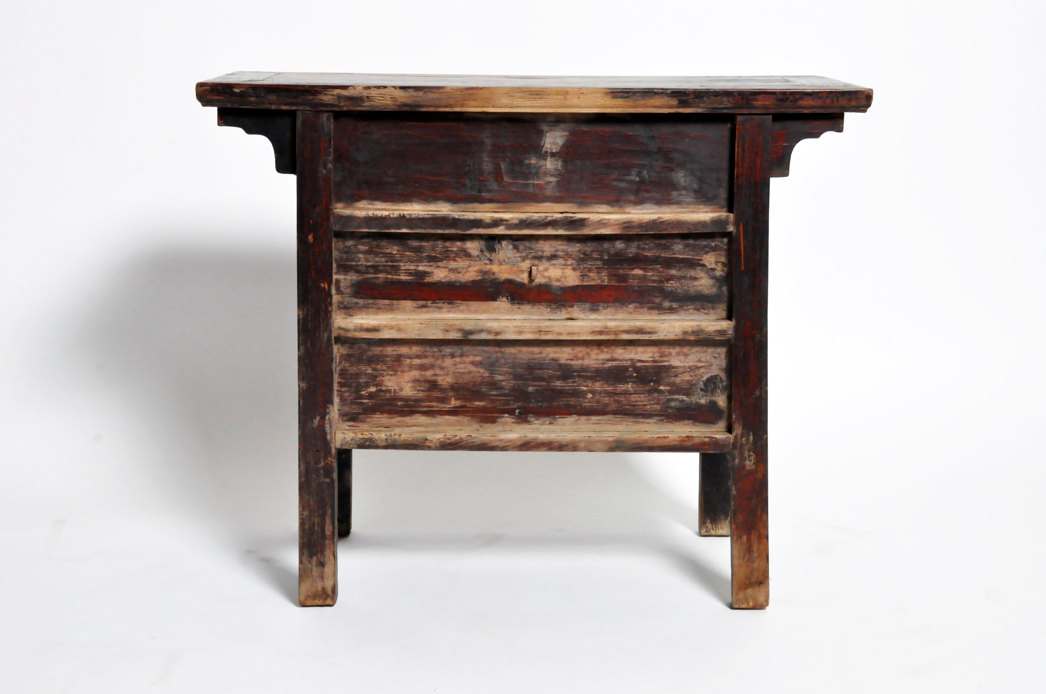 This handsome side chest is from Shanxi, China and made from elmwood, circa Qing dynasty (early 1800s). The piece features three drawers, intricate hard-carved details, and its original oxblood lacquer patina. The finish is completely original-