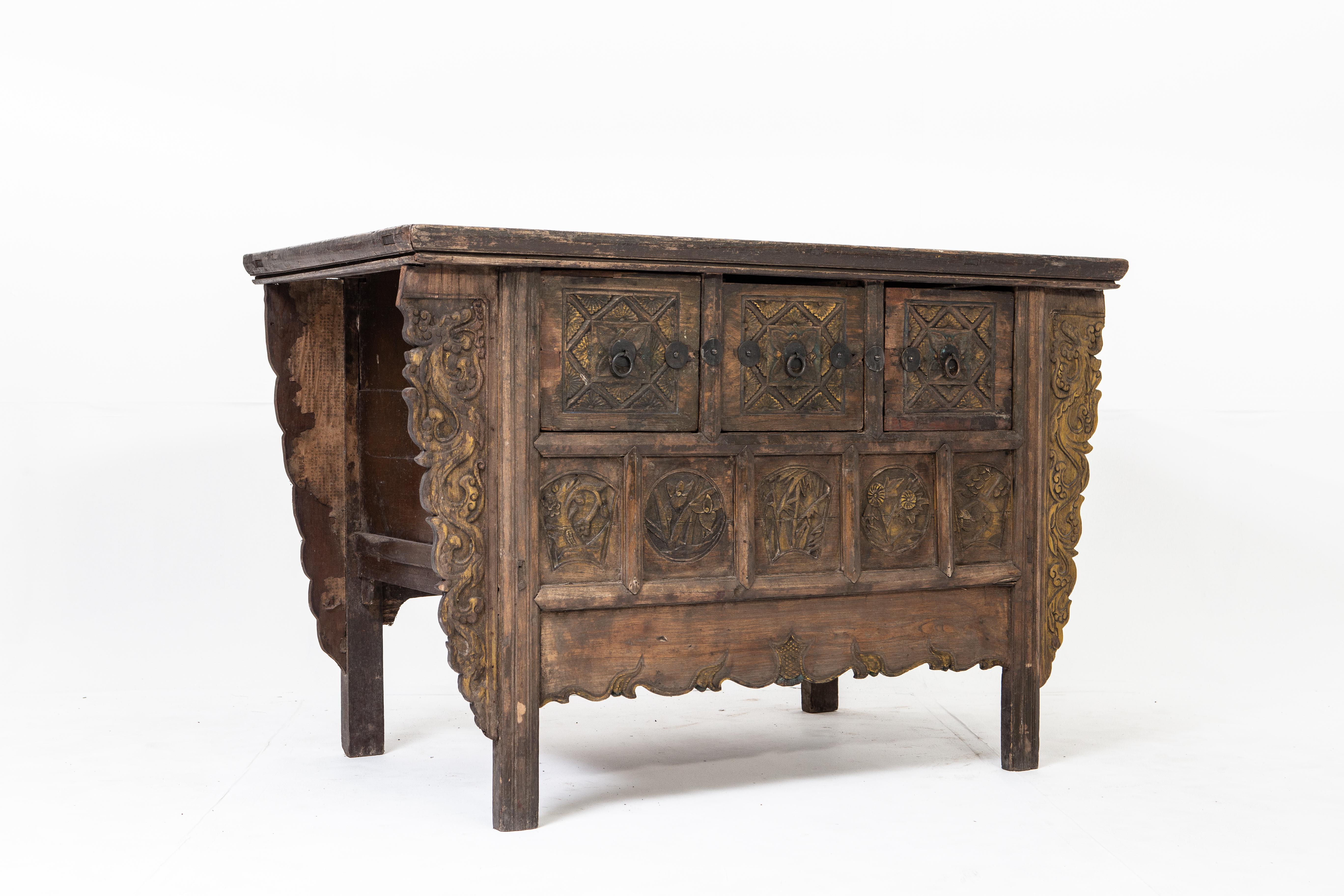 This handsome chest from Henan, China is made of elm wood and dates to the mid-1900s (during the time of Mao Zedong). The piece features intricate hand-carved details, three drawers, and a beautifully aged patina with remnants of its original color.