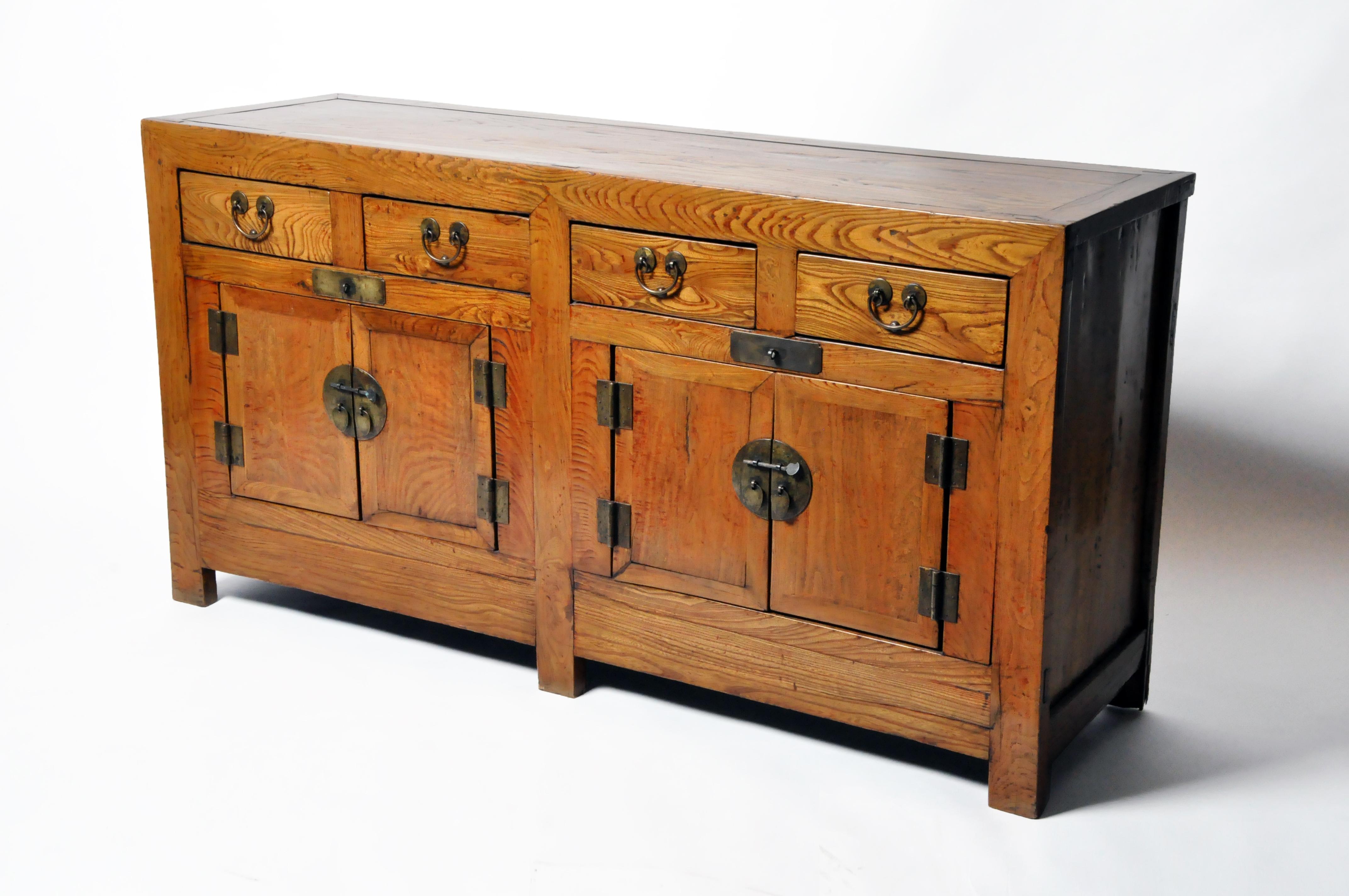 This handsome sideboard is from Tianjin, China, and made from elm wood and dates to the mid-1900s; during the time of Mao Zedong. The piece features four drawers, 2 pairs of doors, and a beautifully aged patina with some remnants of the original
