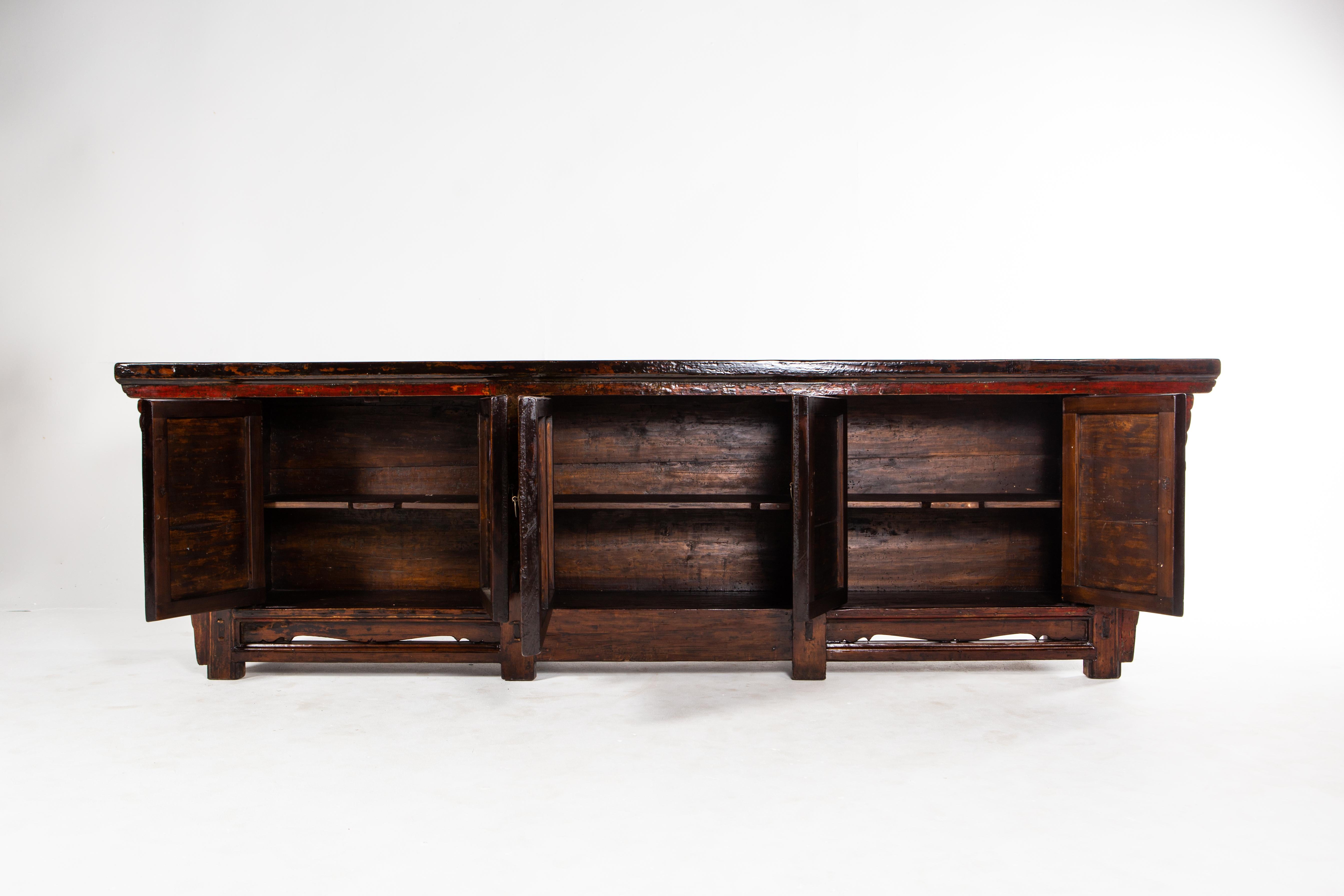 This beautiful sideboard is from Gunsu, China and was made from pine wood and lacquer, circa 1920. The piece features a beautifully aged original patina, 3 pairs of doors, shelves, and some of the original paint still visible. Wear consistent with