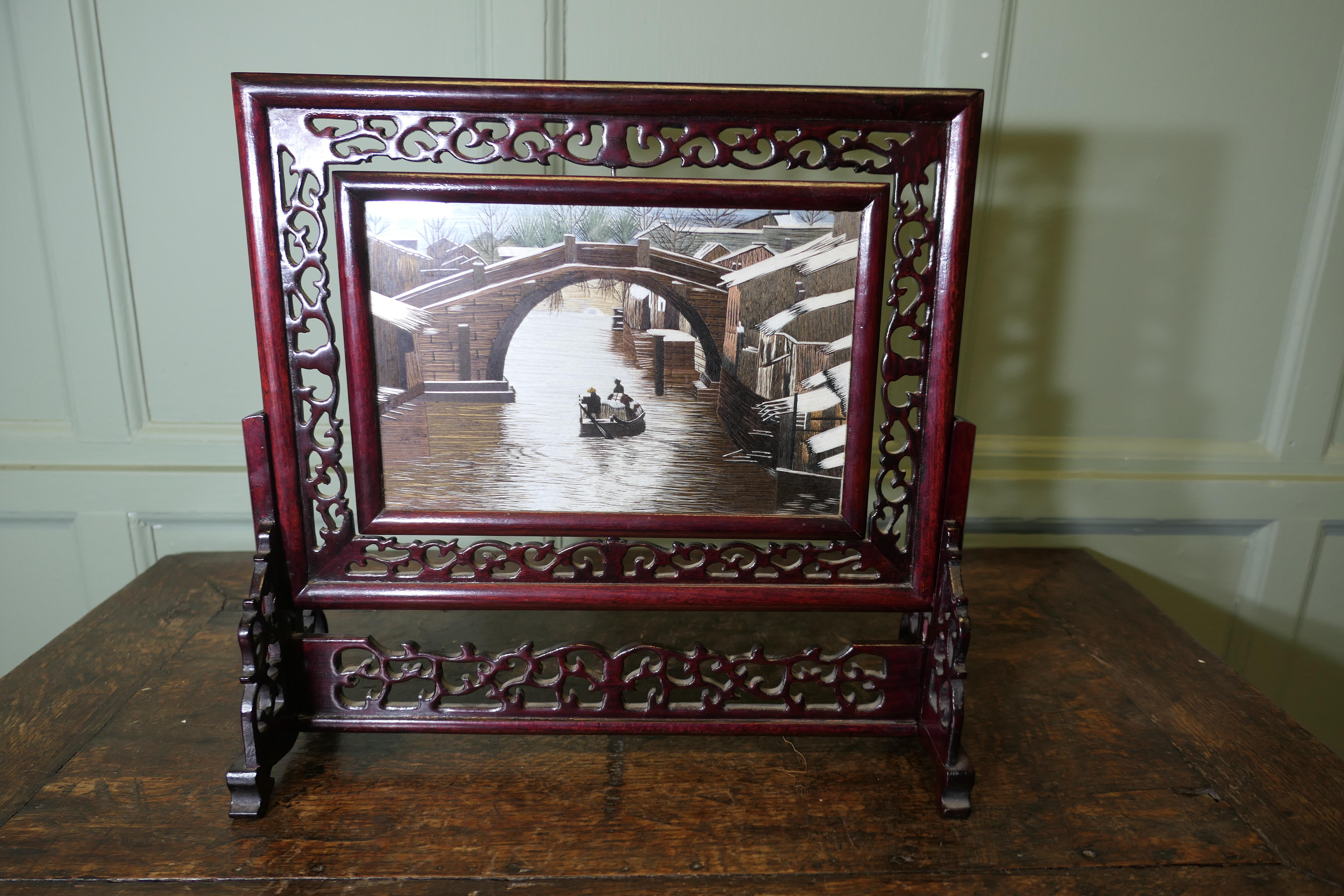 Chinese Silk Table Screen with Intricately Carved Stand

The beautiful double sided painted silk panel shows a boat in the river and a bridge, the framed panel can be lifted out 
The screen is in good Condition, it is 17” high, 18” wide and 6” deep