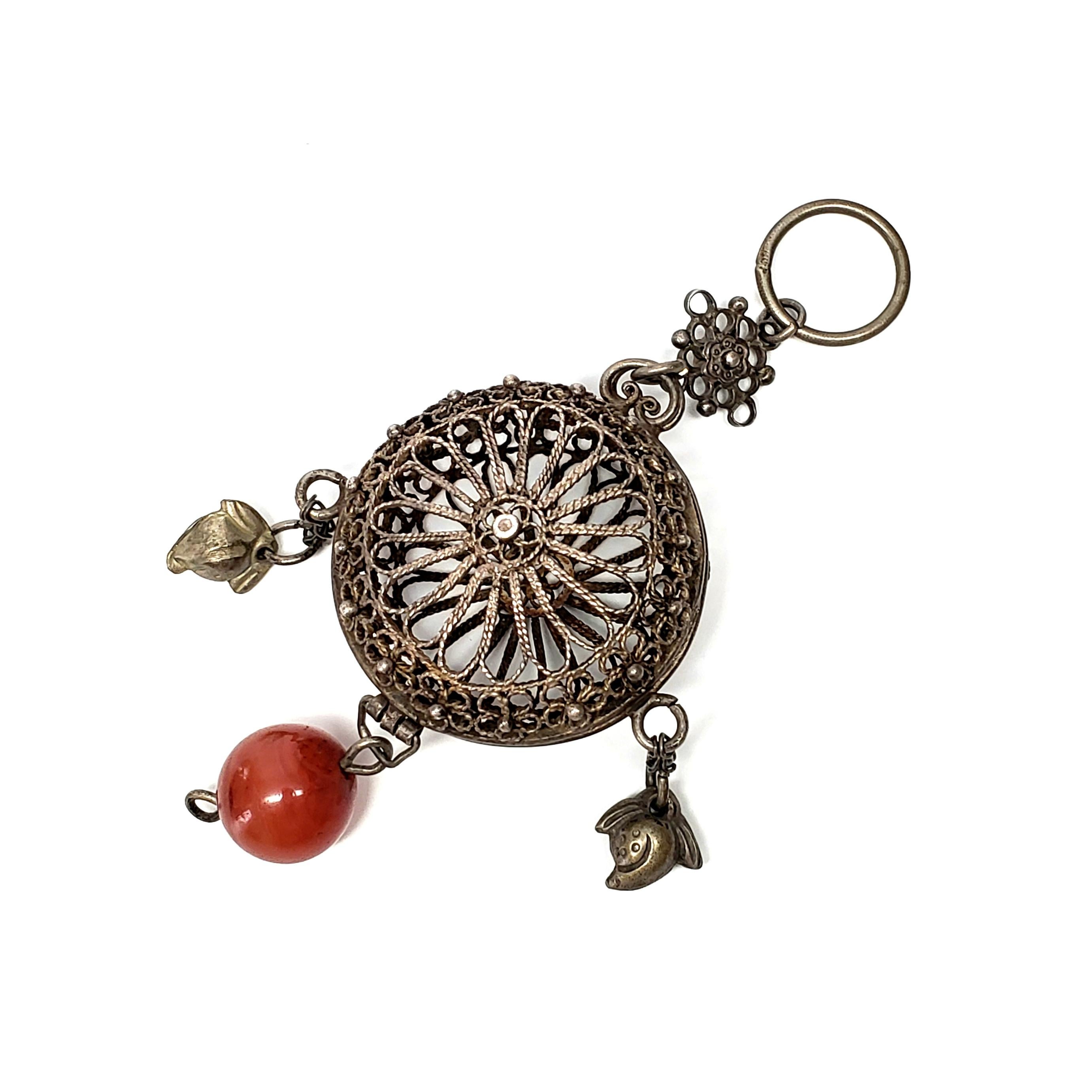 Antique Chinese silver chatelaine cricket cage vinaigrette.

Beautiful filigree floral design with a large round carnelian bead and dangles. Cage opens when loop is removed.

Measures 5