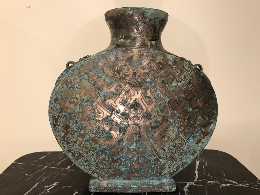A Chinese silver inlaid bronze 'moon vase' modeled after a Warring Sates period, 2-3rd century BC original. Of Classic form, with ring handles, the surface covered with inlaid Archaistic designs. The silver mixed with verdigris patina give this