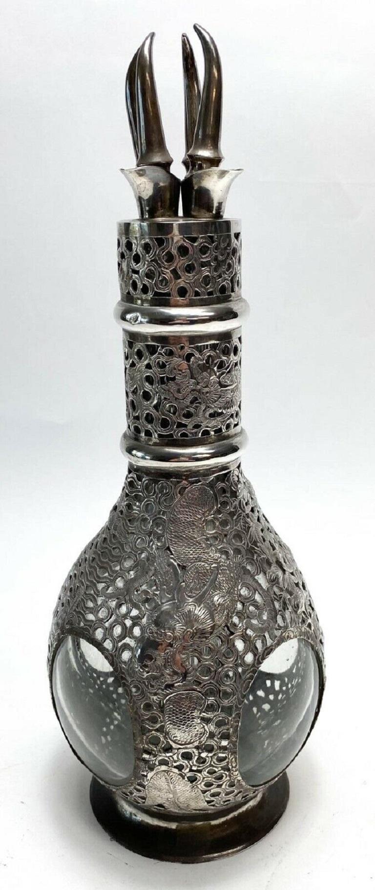 Chinese Silver Overlay Four Compartment Liquor Decanter, c1920

The silver overlay decanter has 4 separate sections for alcohol. Each compartment with a different pattern to the silver overlay. Each side of the decanter depicts bamboo, naval scene,