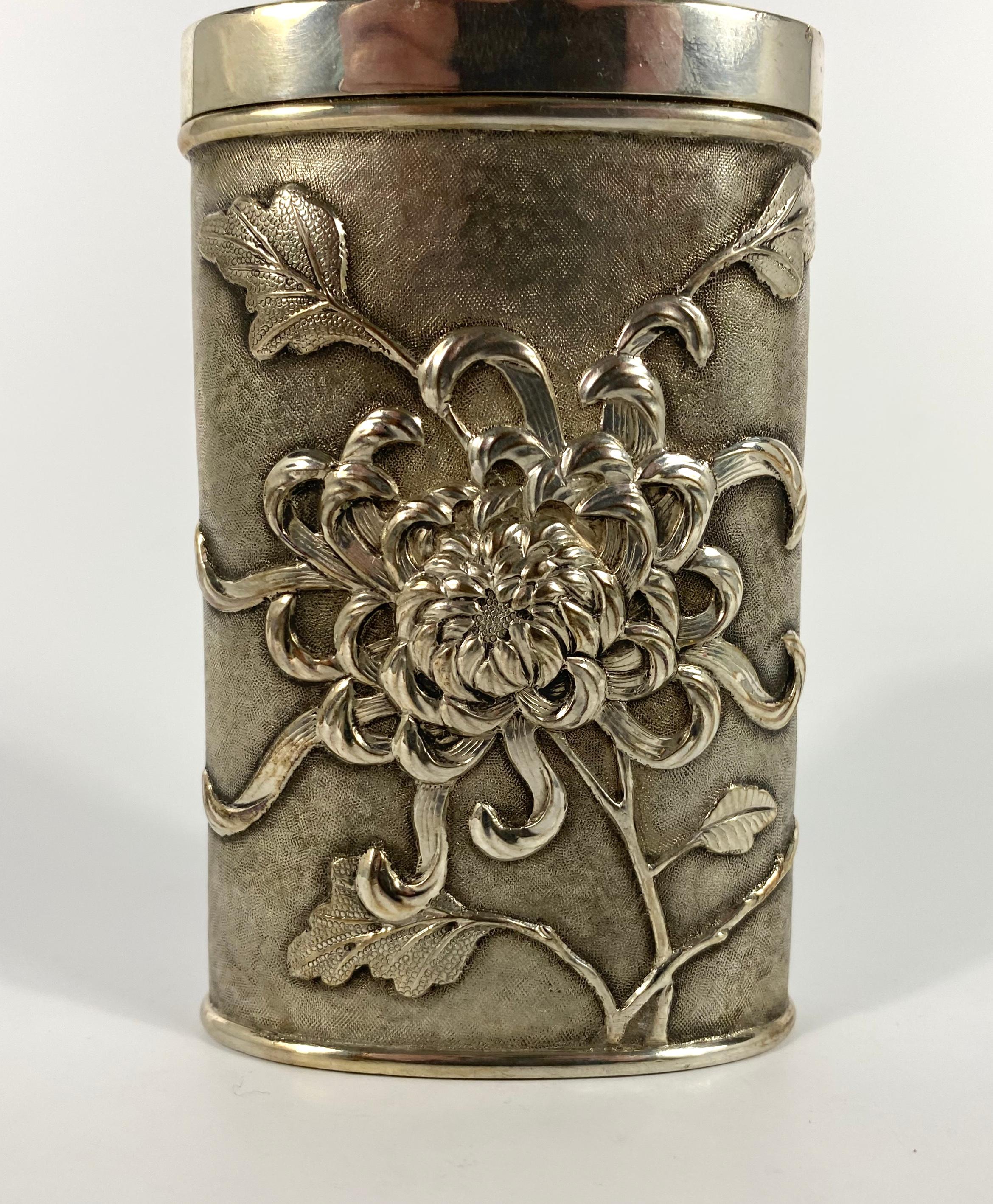 Chinese solid silver talcum powder dispenser, Luen Wo, Shanghai, circa 1900. Decorated to either side with flowering chrysanthemum, on a stippled ground.
The detachable top section, with a swivel pierced cover, pierced to dispense the