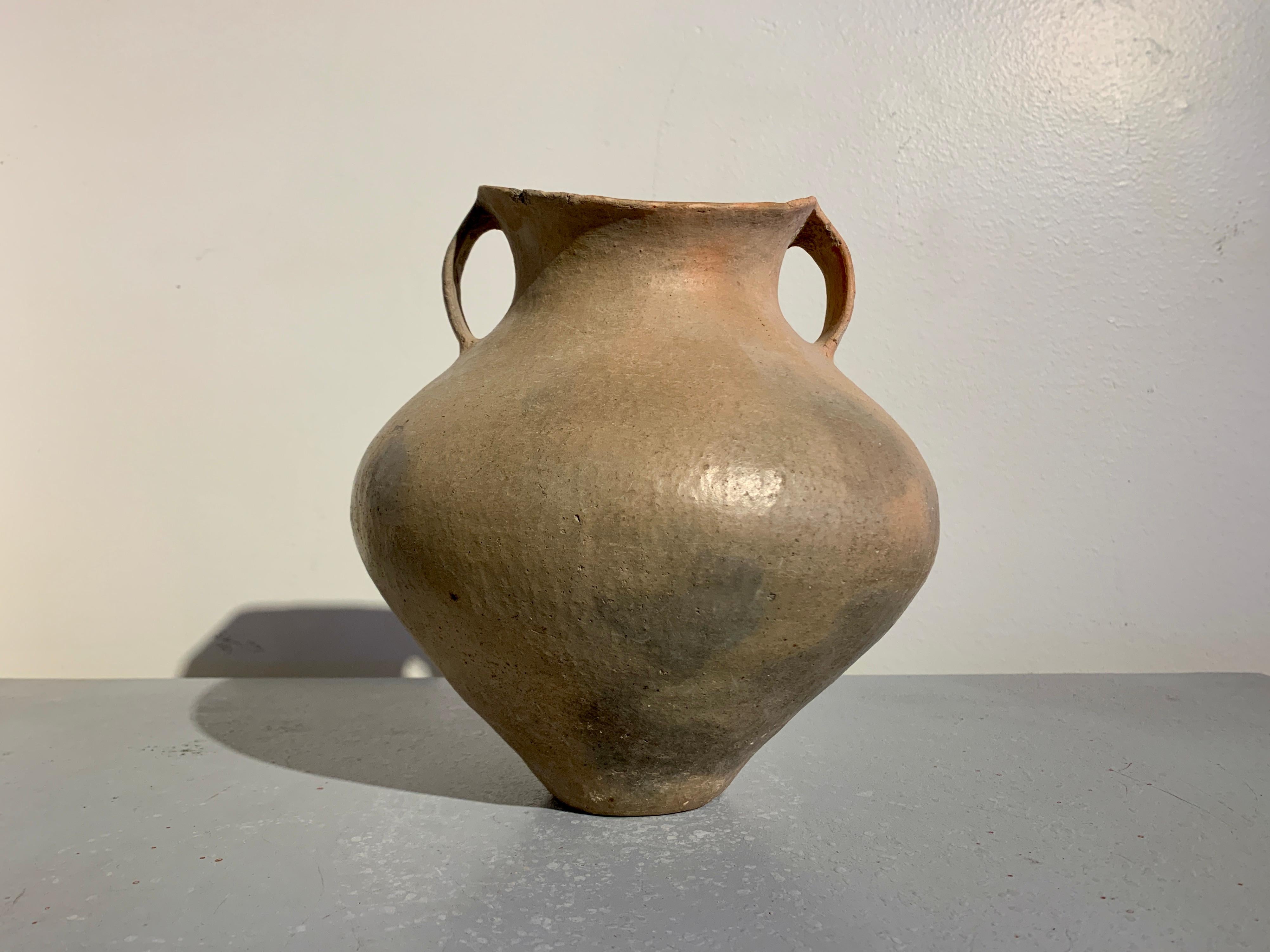 A striking Chinese Neolithic to Bronze Age burnished red pottery double handled saddle mouth storage jar, Siwa Culture (circa 1500 to 1100 BC), modern day Gansu Province, China. 

The storage jar beautifully proportioned and featuring voluptuous