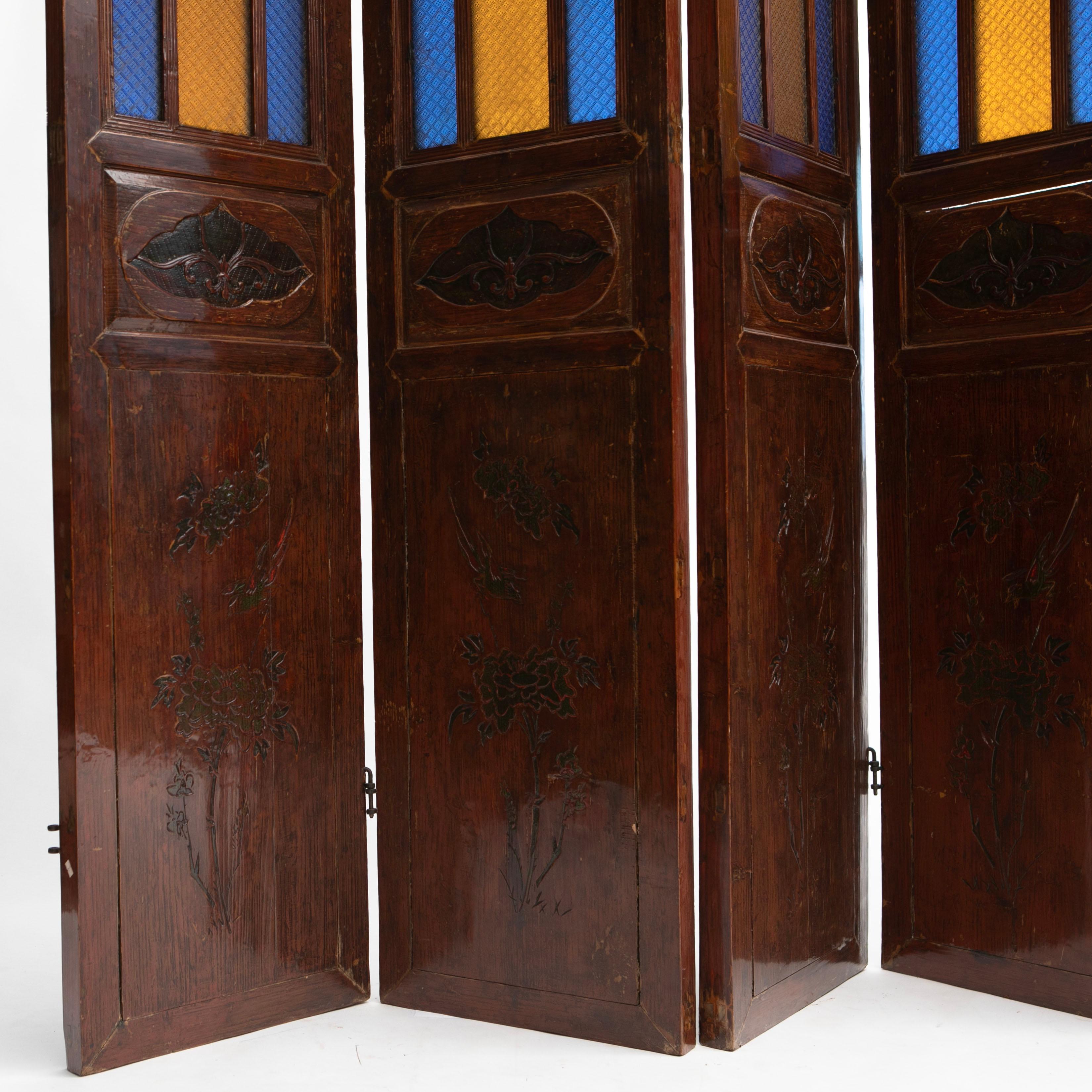 Chinese six-panel Art Nouveau room divider or screen.
Wood with original lacquer.
Each panel has 9 colored glass panels and is adorned with decorative wood carved decorations on the lower part of the screens. Original lacquer graced with a rich