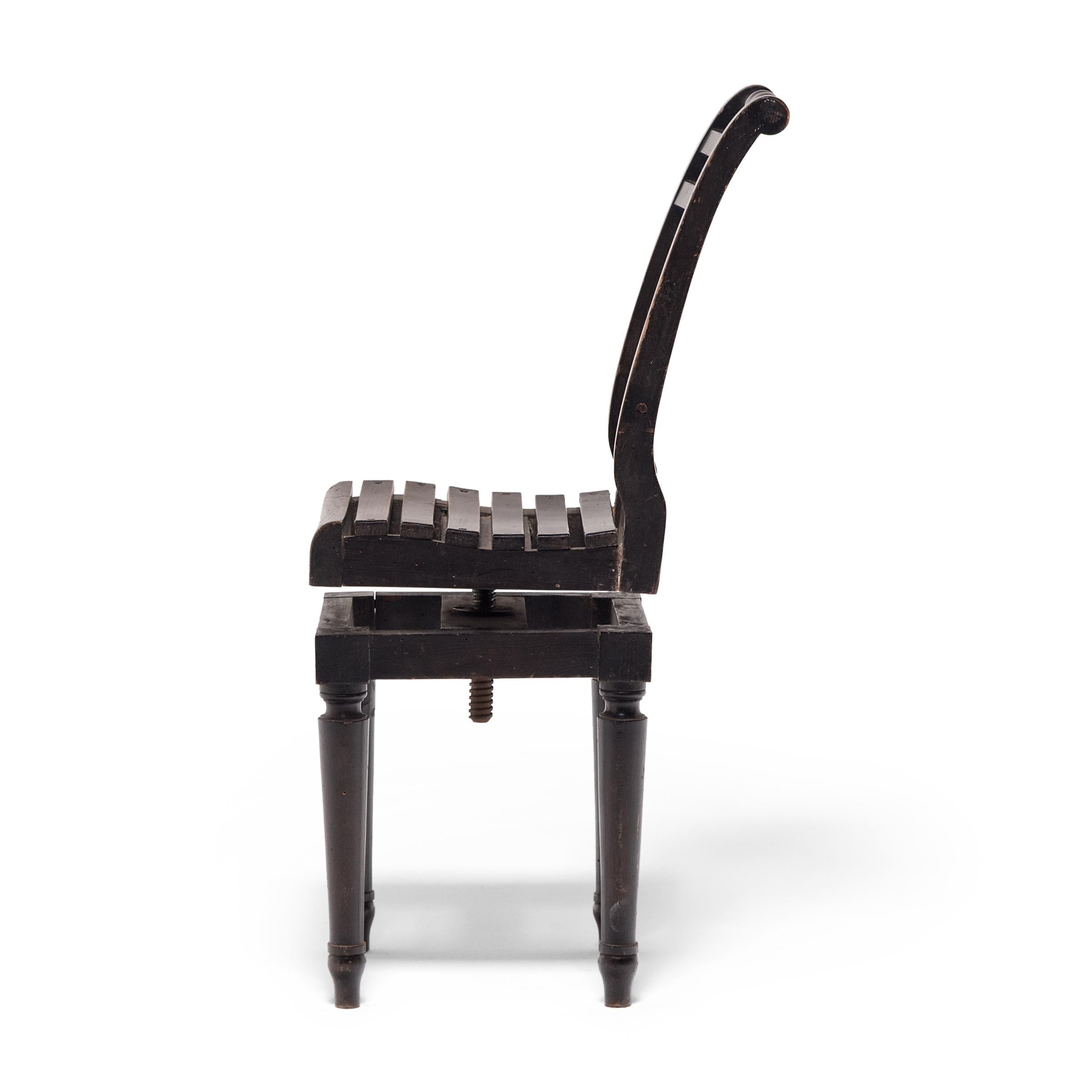 This unusual early 20th-century chair can be raised or lowered with just a turn of the seat. A chair in two parts, the slatted seat and high back are connected to the square base by a threaded iron rod and changes in height as its turned. Turned