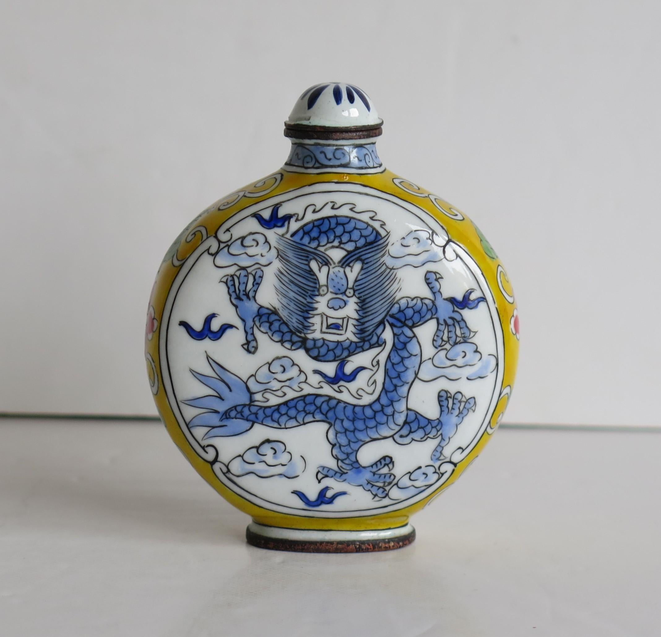 This is a Chinese enamelled snuff bottle, with a hand painted dragon on either side, with coloured side borders and a four character mark to the base, which we date to the 1940s.

The circular body of this bottle is made of copper or bronze. There
