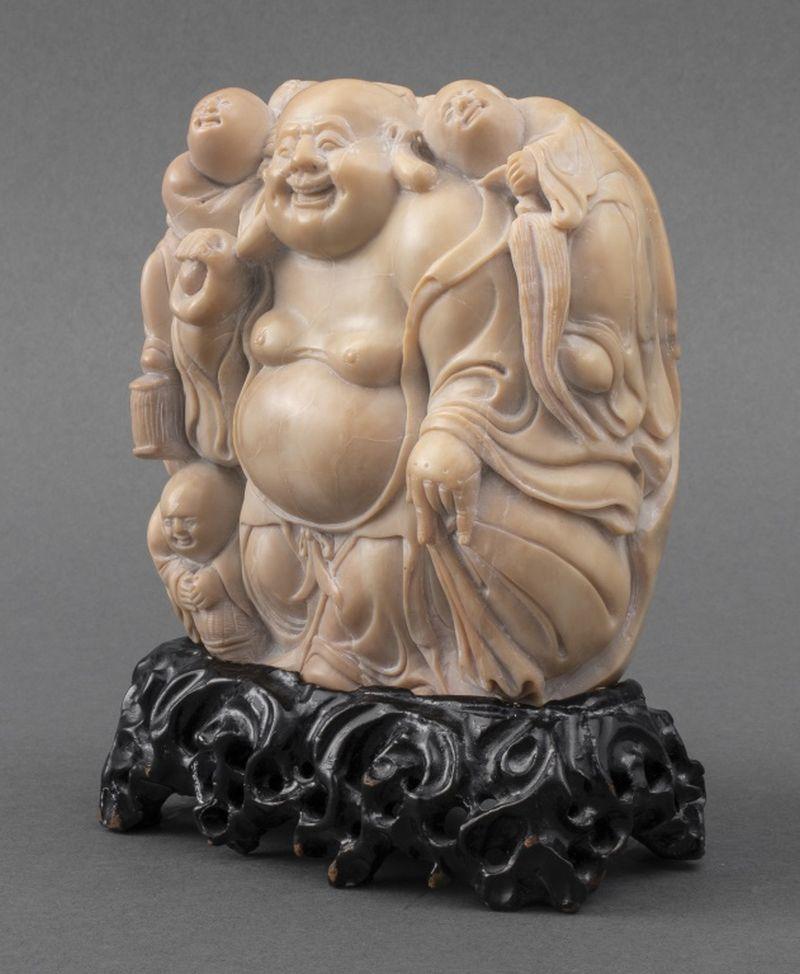 Chinese Soapstone Buddha Carving on Stand, smiling Buddha with three children holding objects including the peaches of immortality, on a fitted pierced black stand. 5.25