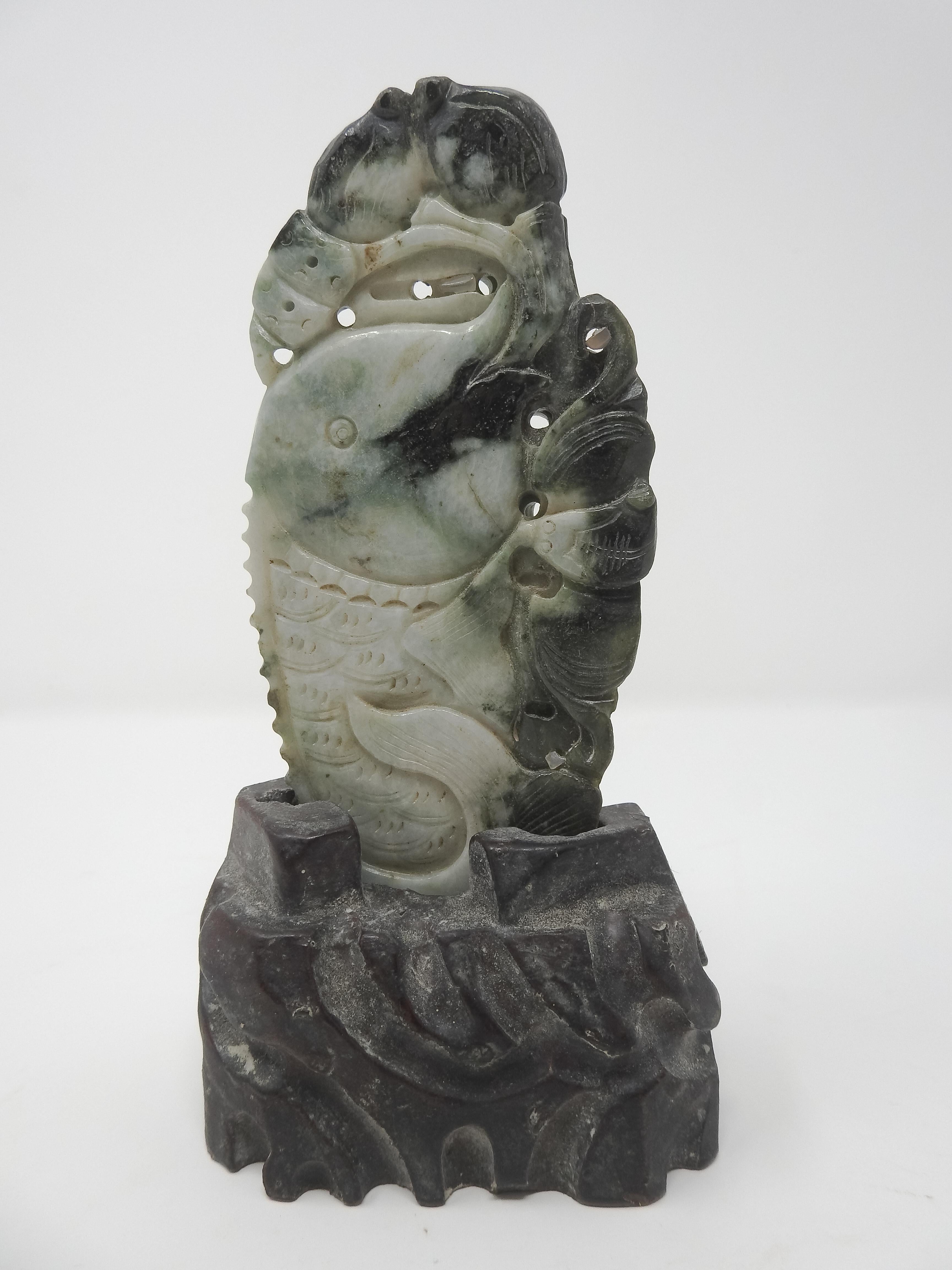 Offering this Chinese soapstone carving on a stone base. The base has channels that are cutout in gentle curves. The soapstone is double sided and has a Koi fish carved in. Around the fish is many different scrollwork details.