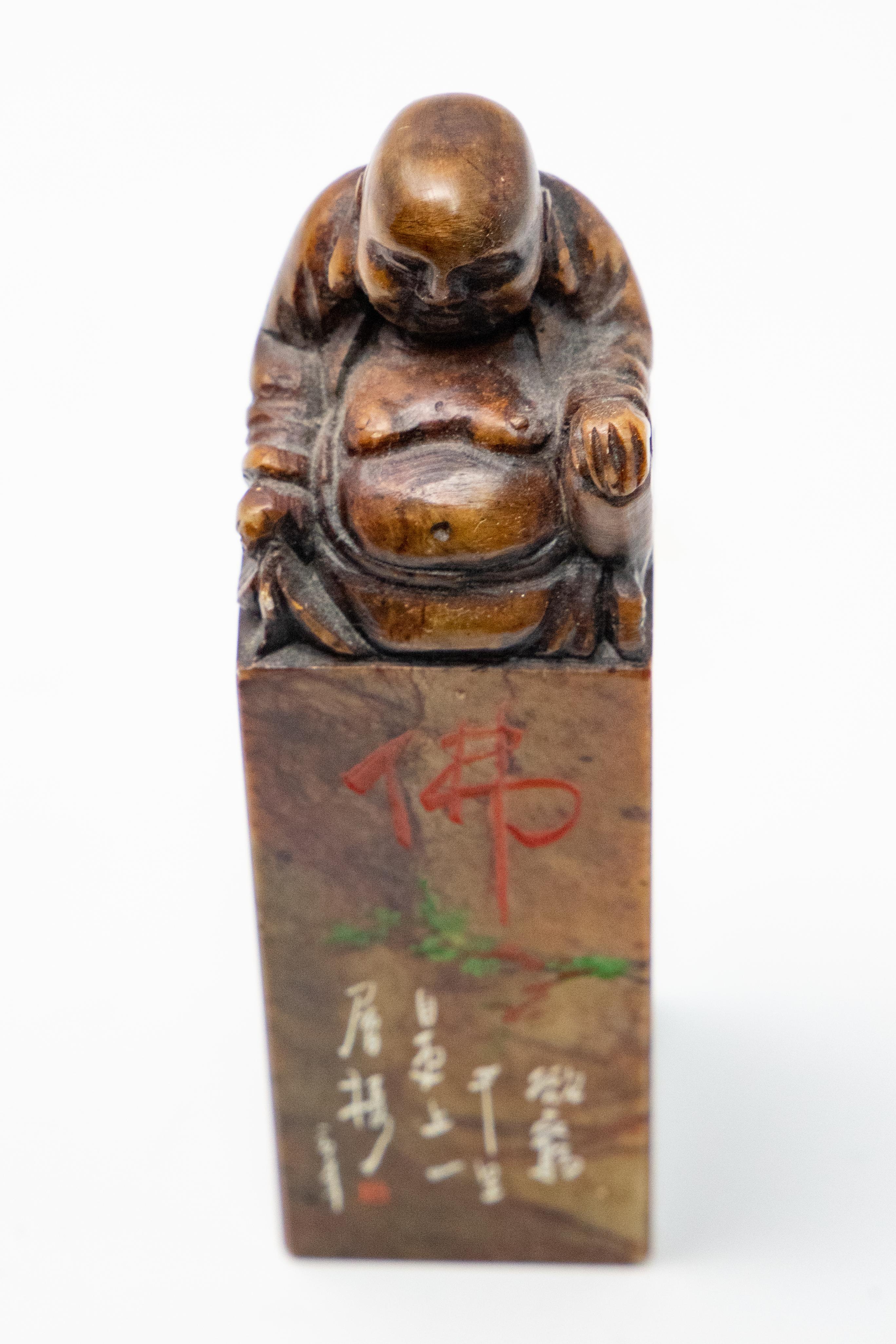 Offering a Chinese soapstone chop seal. On top it depicts a Shoushan Laughing Buddha. Holding one hand up with palm down, and the other is holding fabric. He sits atop a square tall base and has markings to one side. Bottom is blank.

History of